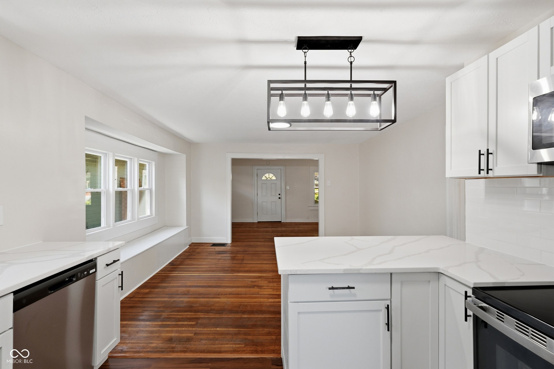 Modern kitchen featuring white shaker cabinetry, stainless steel appliances, and sleek white countertops