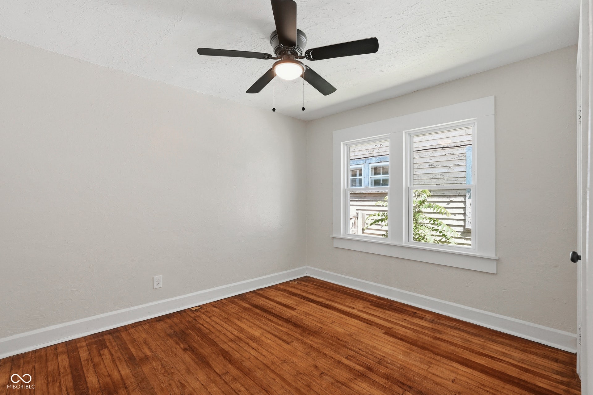Hardwood flooring, painted walls, white trim, dual windows, and an overhead ceiling fan with lighting