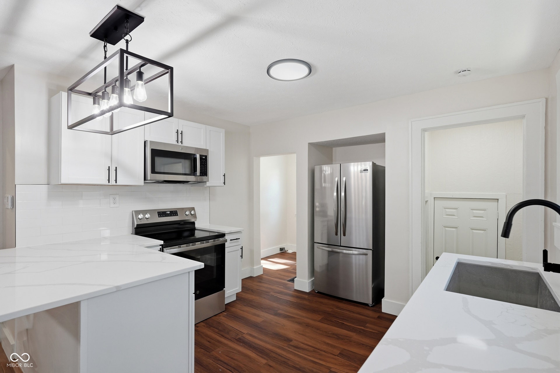 Kitchen featuring white cabinetry, stainless steel appliances, white subway tile backsplash, white countertops, and wood-finish flooring