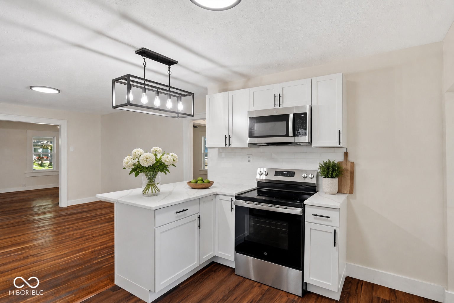 Virtually Altered - Modern kitchen featuring white cabinetry, stainless steel appliances, and a white subway tile backsplash