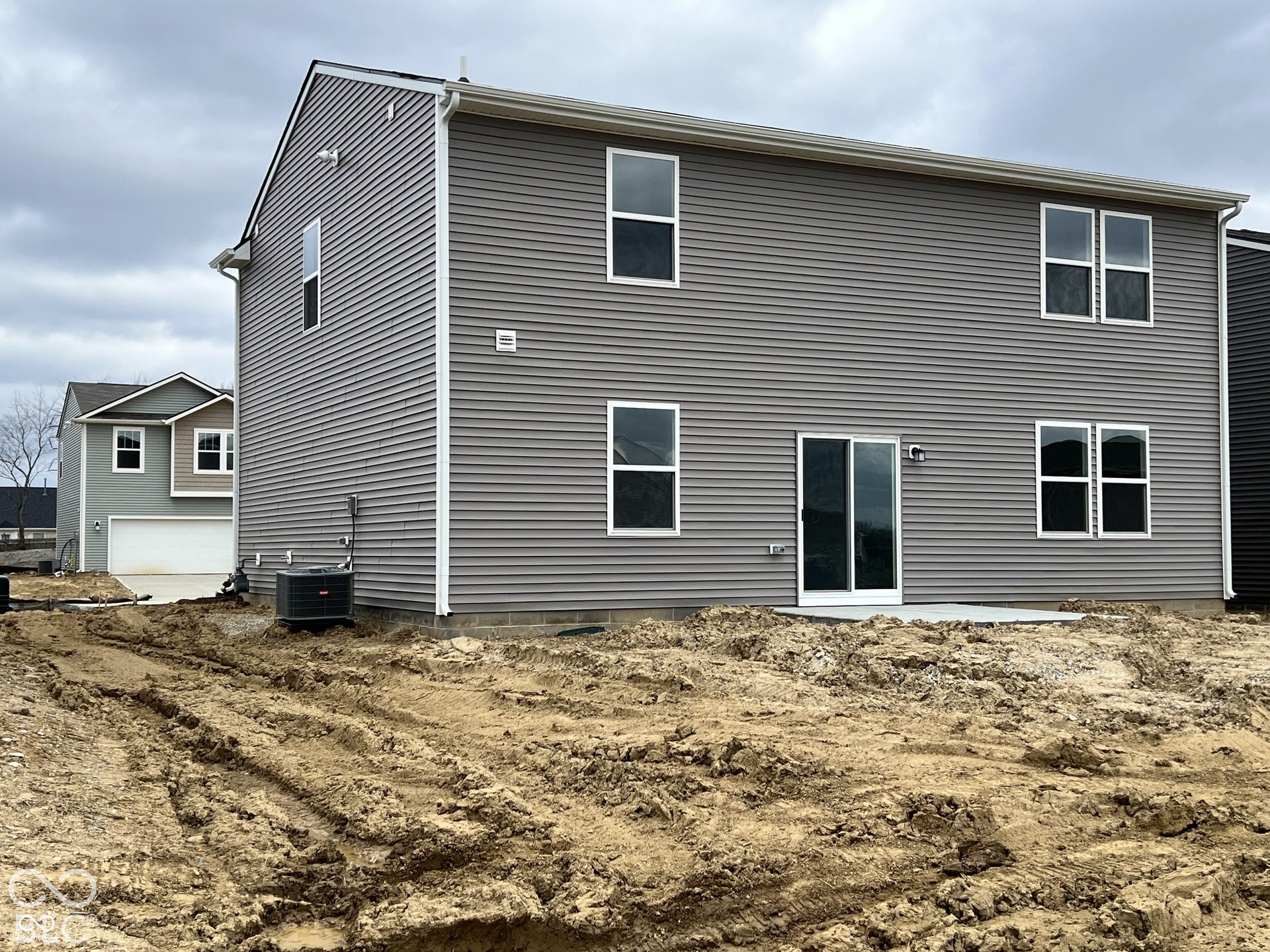 Two-story siding exterior with multiple windows, sliding glass door, and a concrete patio