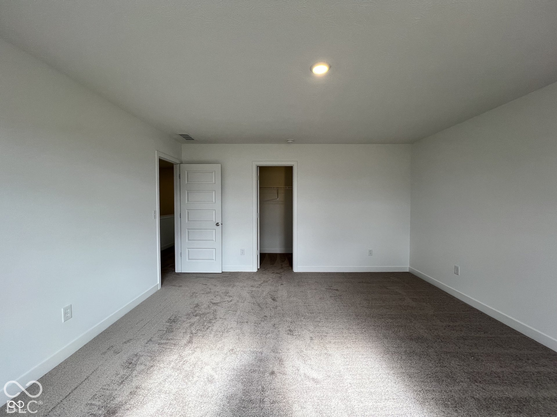 Recessed ceiling lighting, white walls, five-panel interior door, and neutral carpet flooring