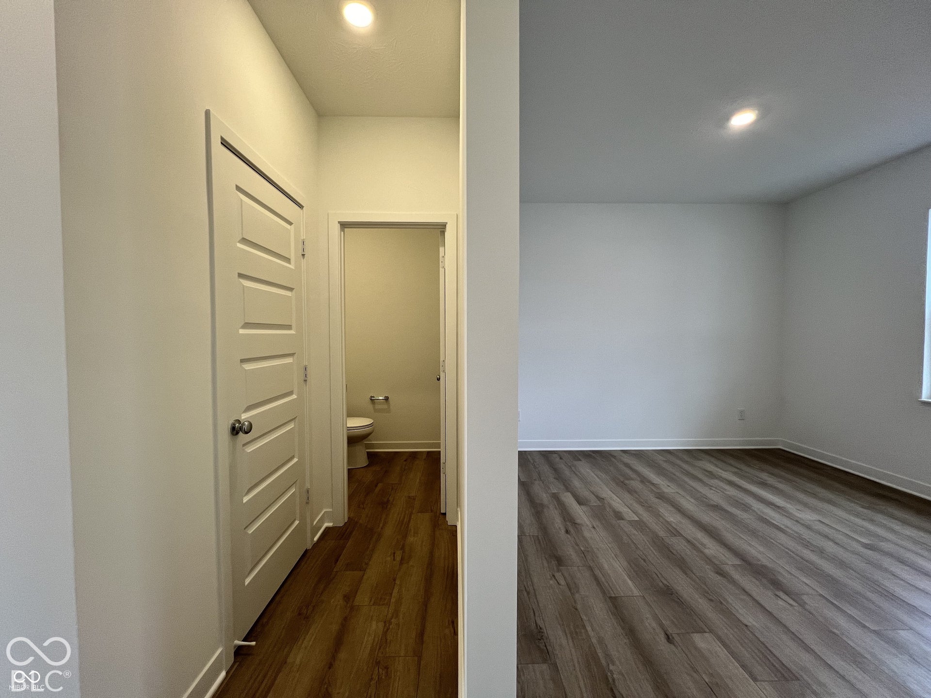 Wood-finish flooring throughout, bright white walls, recessed ceiling lighting, and panel interior doors