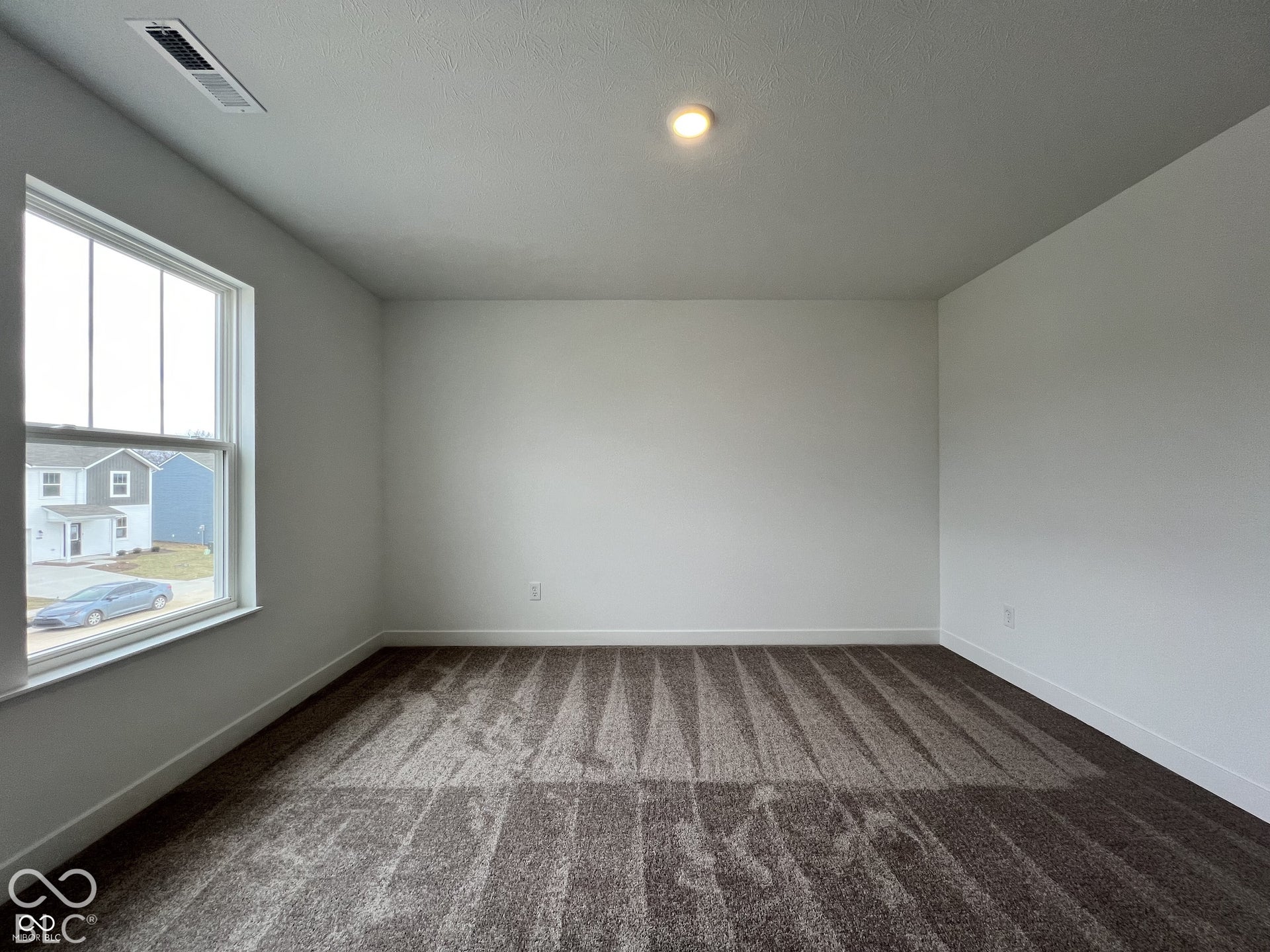 Recessed ceiling lighting, patterned carpet flooring, white walls, and a large window