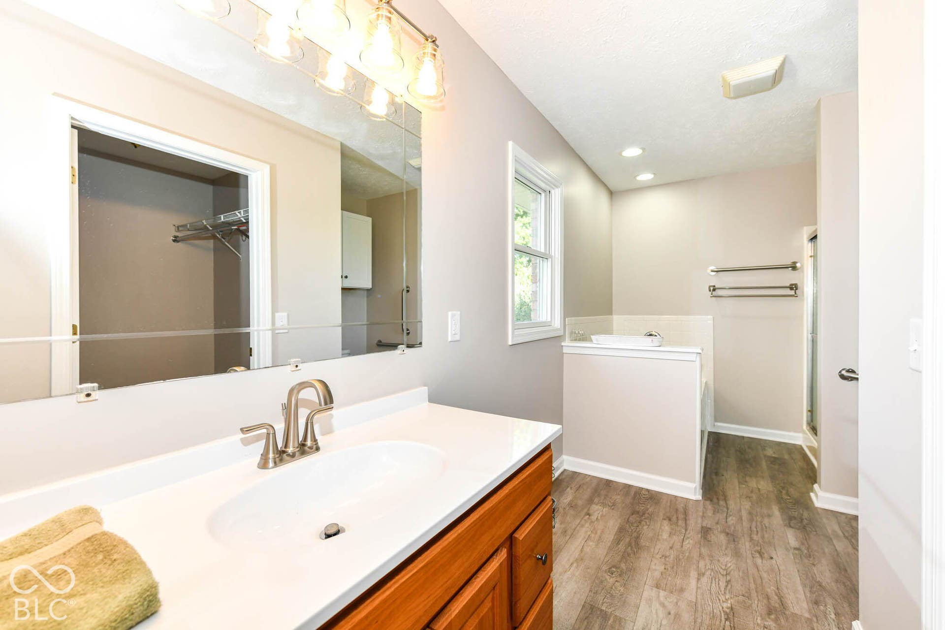 Vanity with a single basin sink, brushed nickel faucet, large wall mirror, and overhead lighting