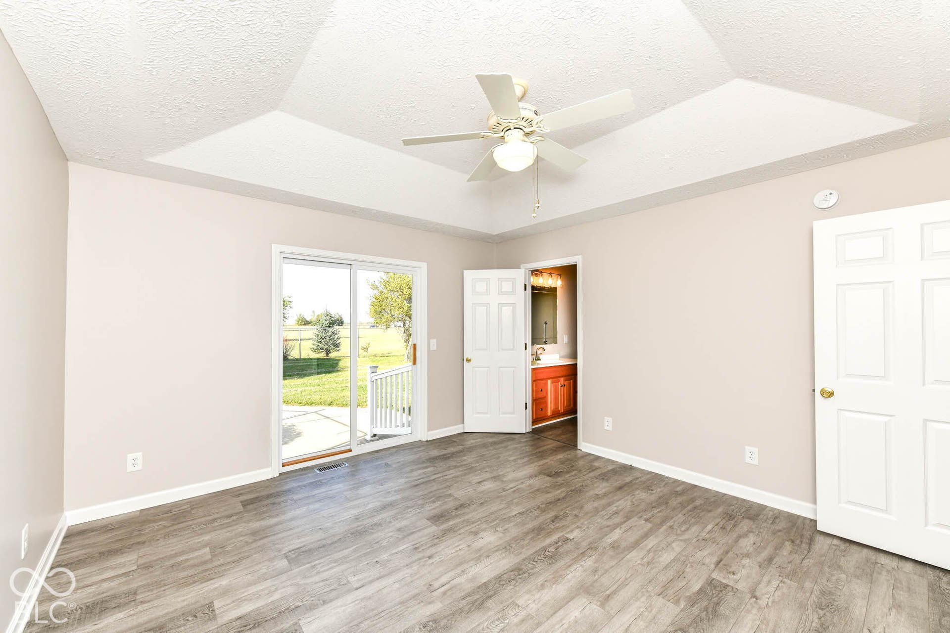 Tray ceiling, ceiling fan, wood-finish flooring, sliding glass door, white trim