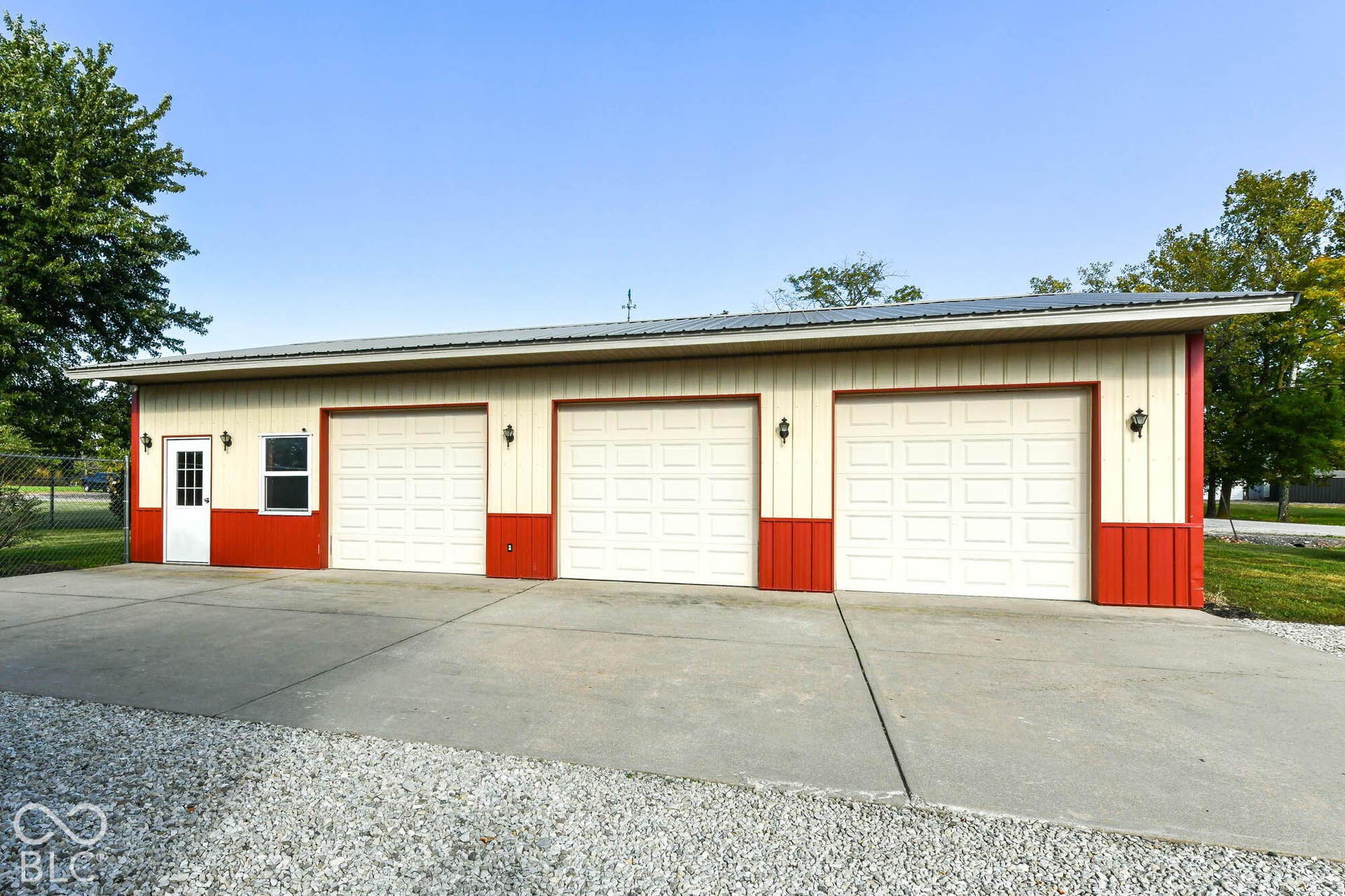Three-car garage with white paneled doors, red and beige siding, and a metal roof