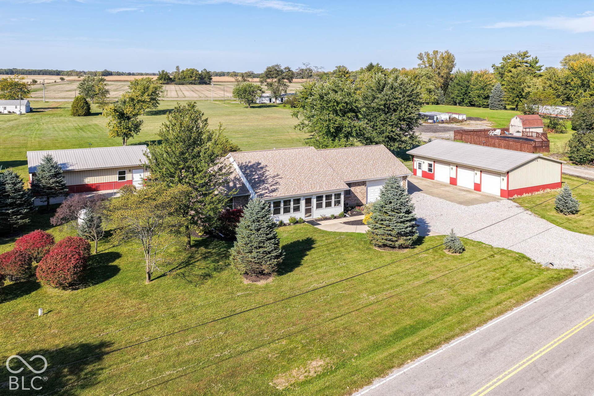 Ranch-style residence with a light-toned shingle roof, established evergreen landscaping, and a gravel driveway