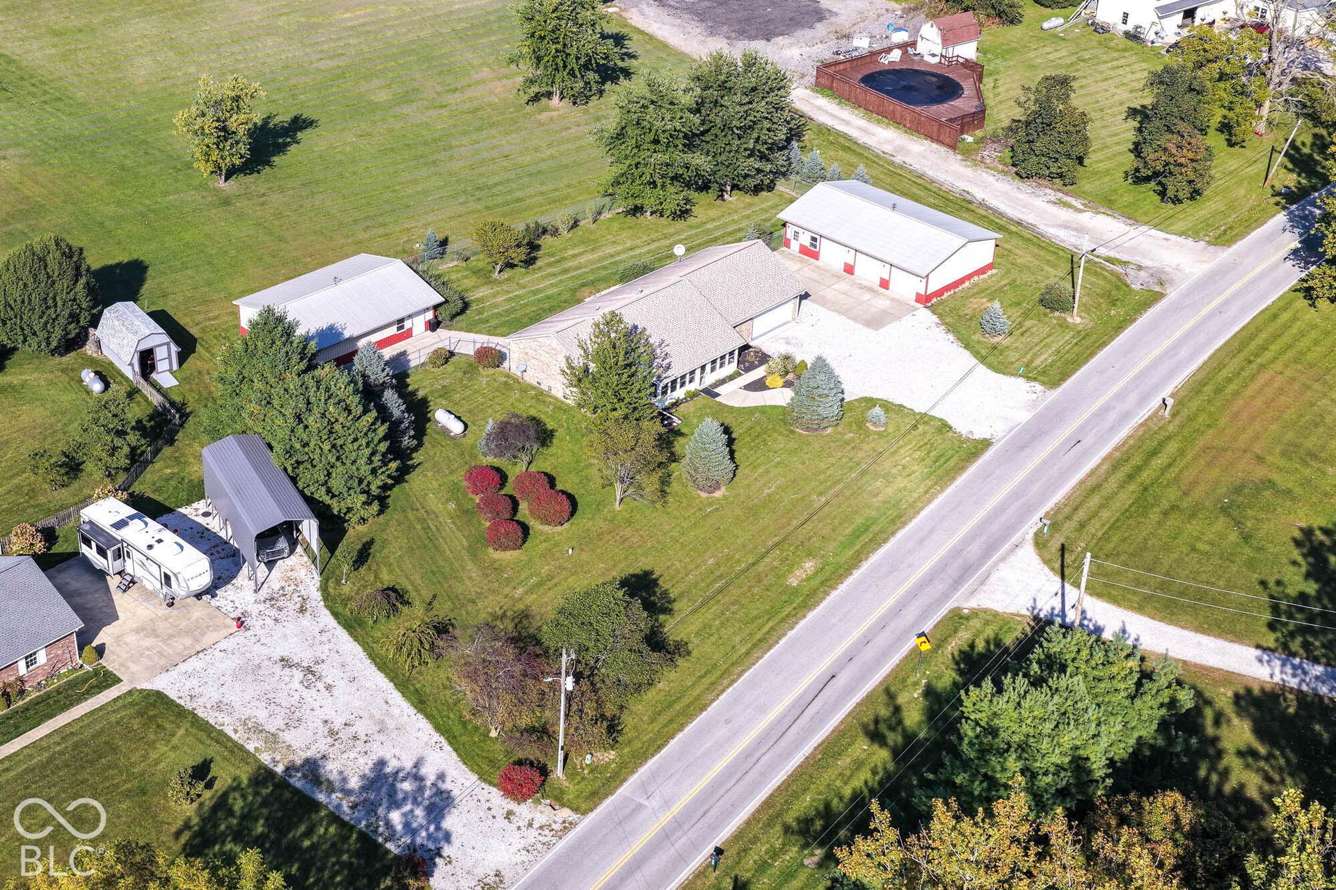 Expansive lot featuring a primary residence, a large outbuilding with multiple bays, a secondary outbuilding, and a gravel driveway