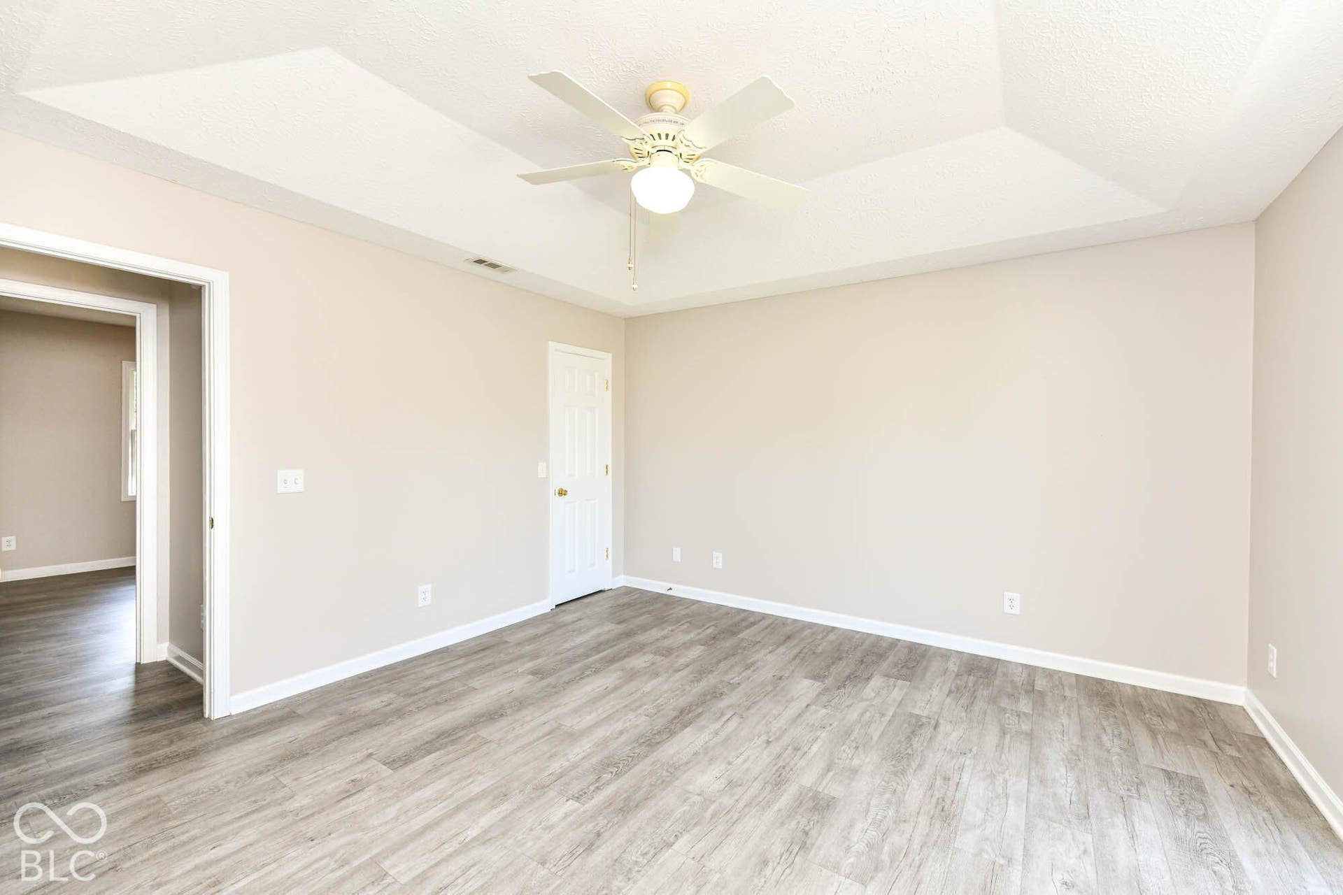 Tray ceiling, ceiling fan, wood-finish flooring, white baseboards, and neutral wall tones