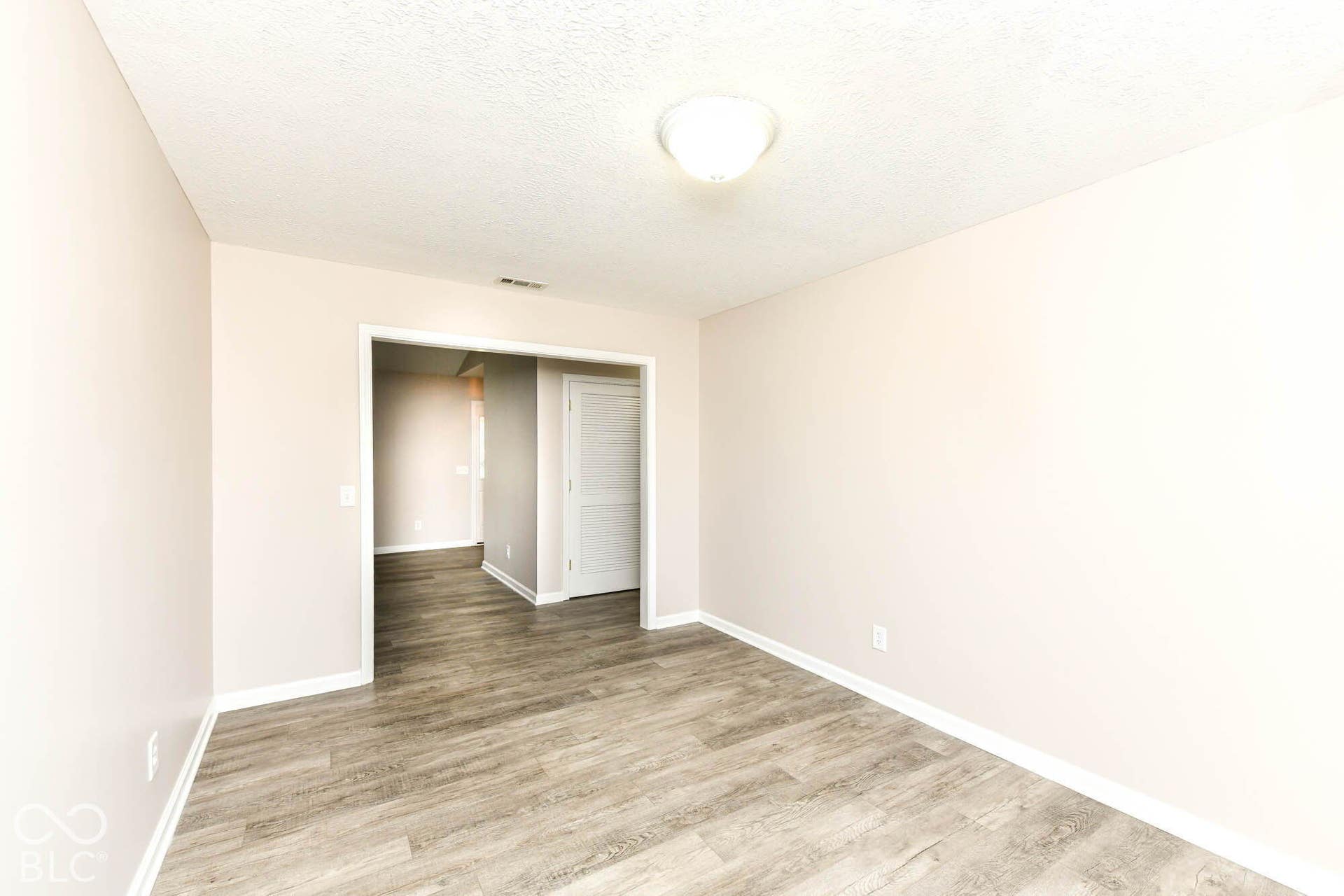Neutral wall paint, wood-finish flooring, white trim, flush-mount ceiling light