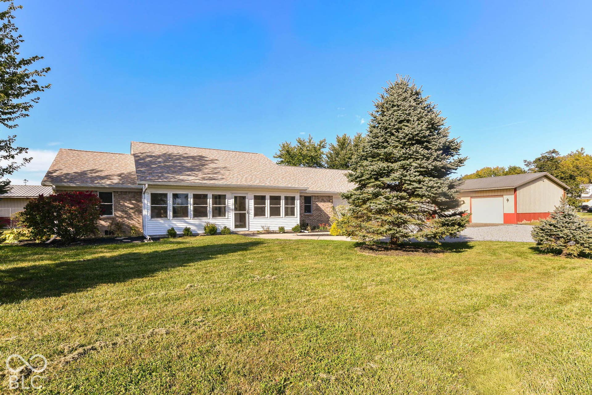 Ranch-style residence featuring a brick and siding exterior, multiple windows, and a gravel driveway
