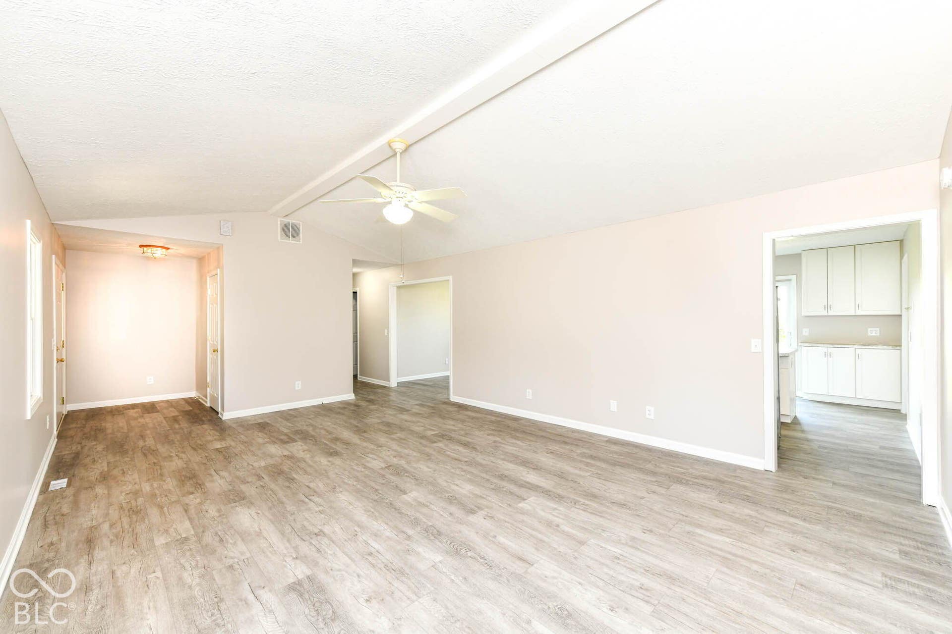 Spacious living area featuring wood-finish flooring, vaulted ceiling, and a ceiling fan