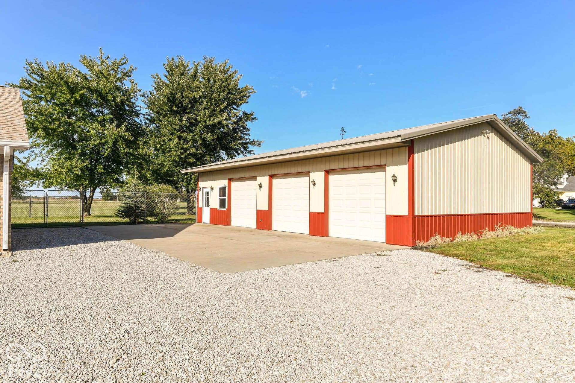 Three-bay garage with metal siding, concrete apron, and gravel driveway
