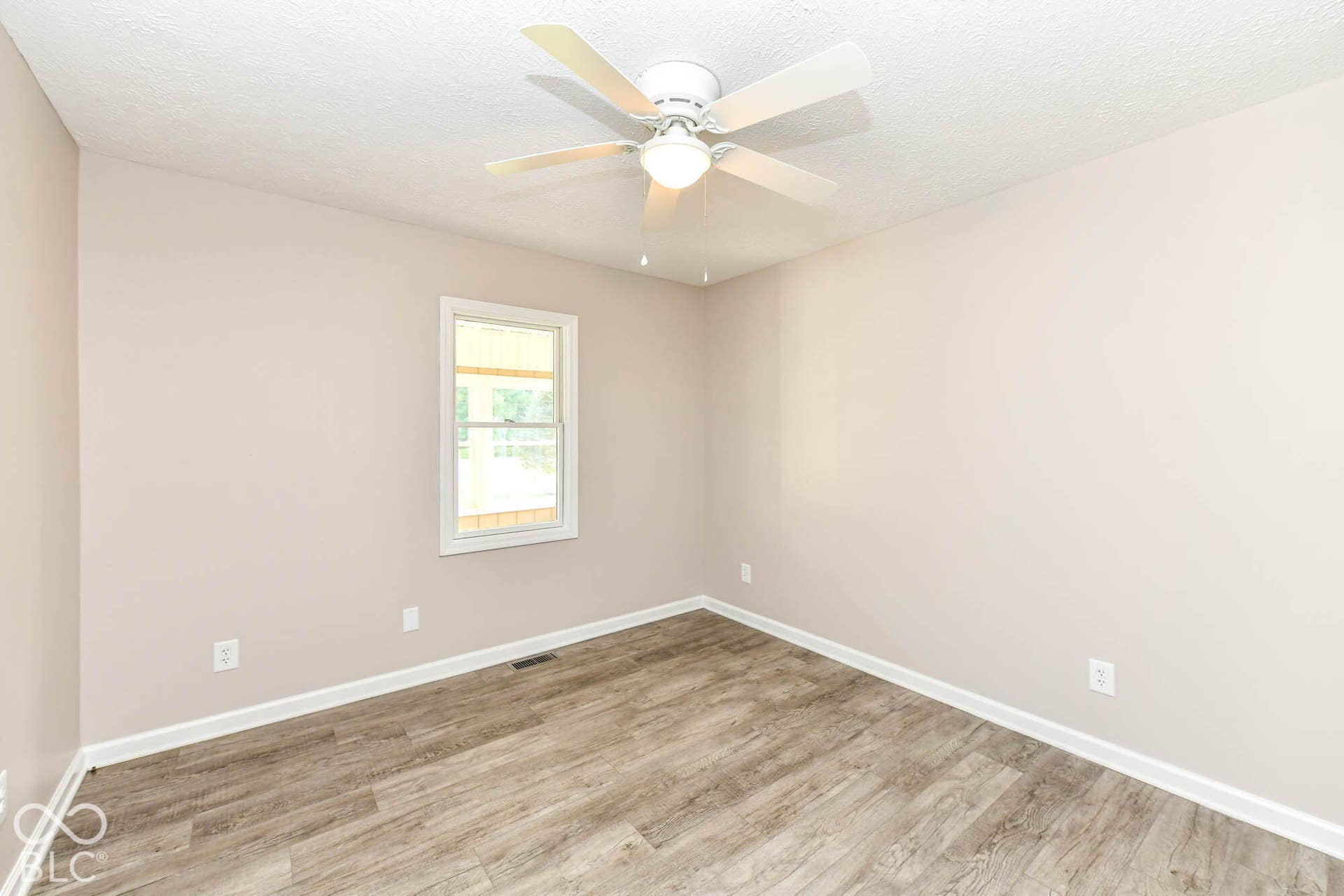 Wood-finish flooring, neutral wall tones, and a ceiling fan with integrated lighting