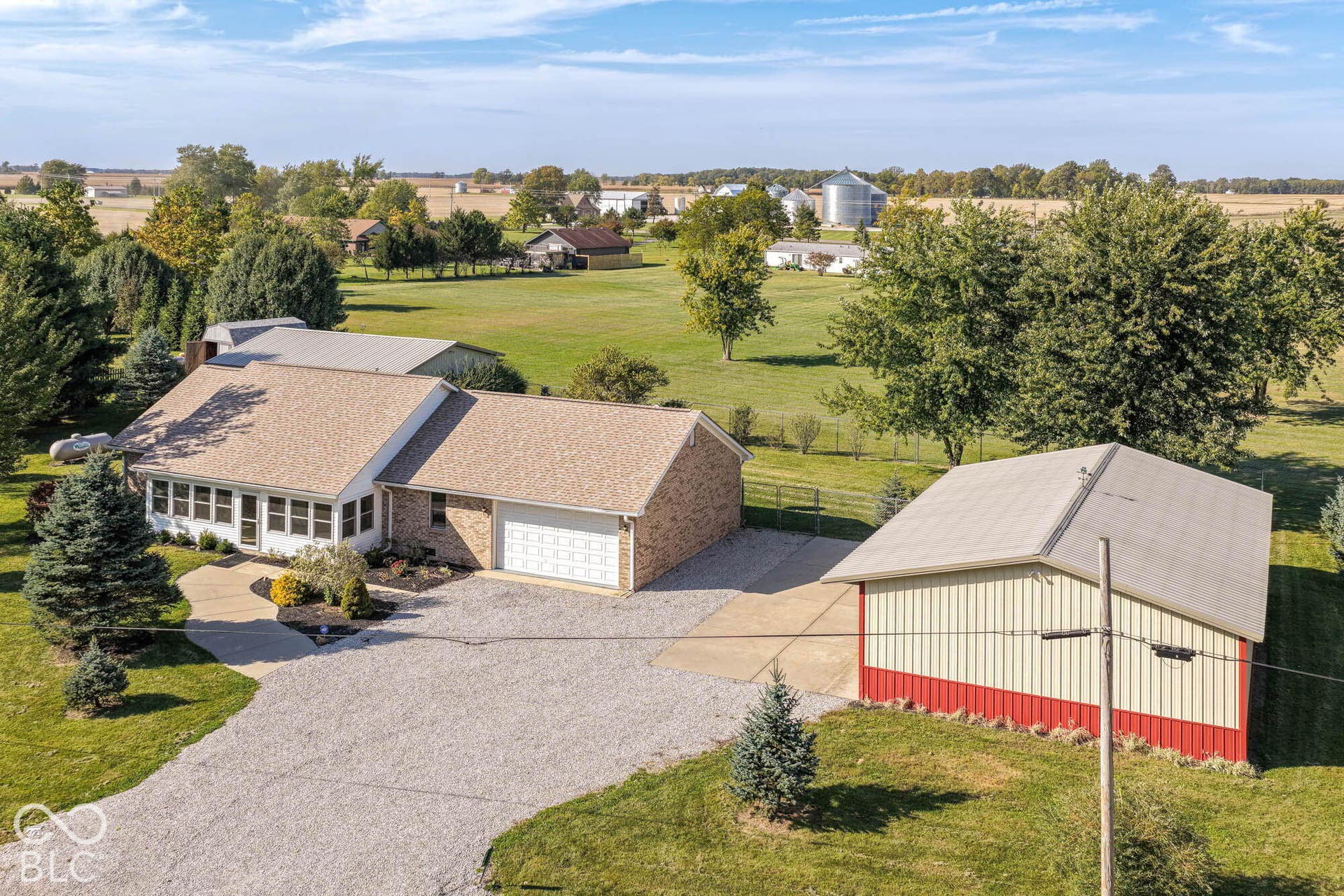 Brick exterior residence with an attached two-car garage, gravel driveway, and a separate utility building with a metal roof