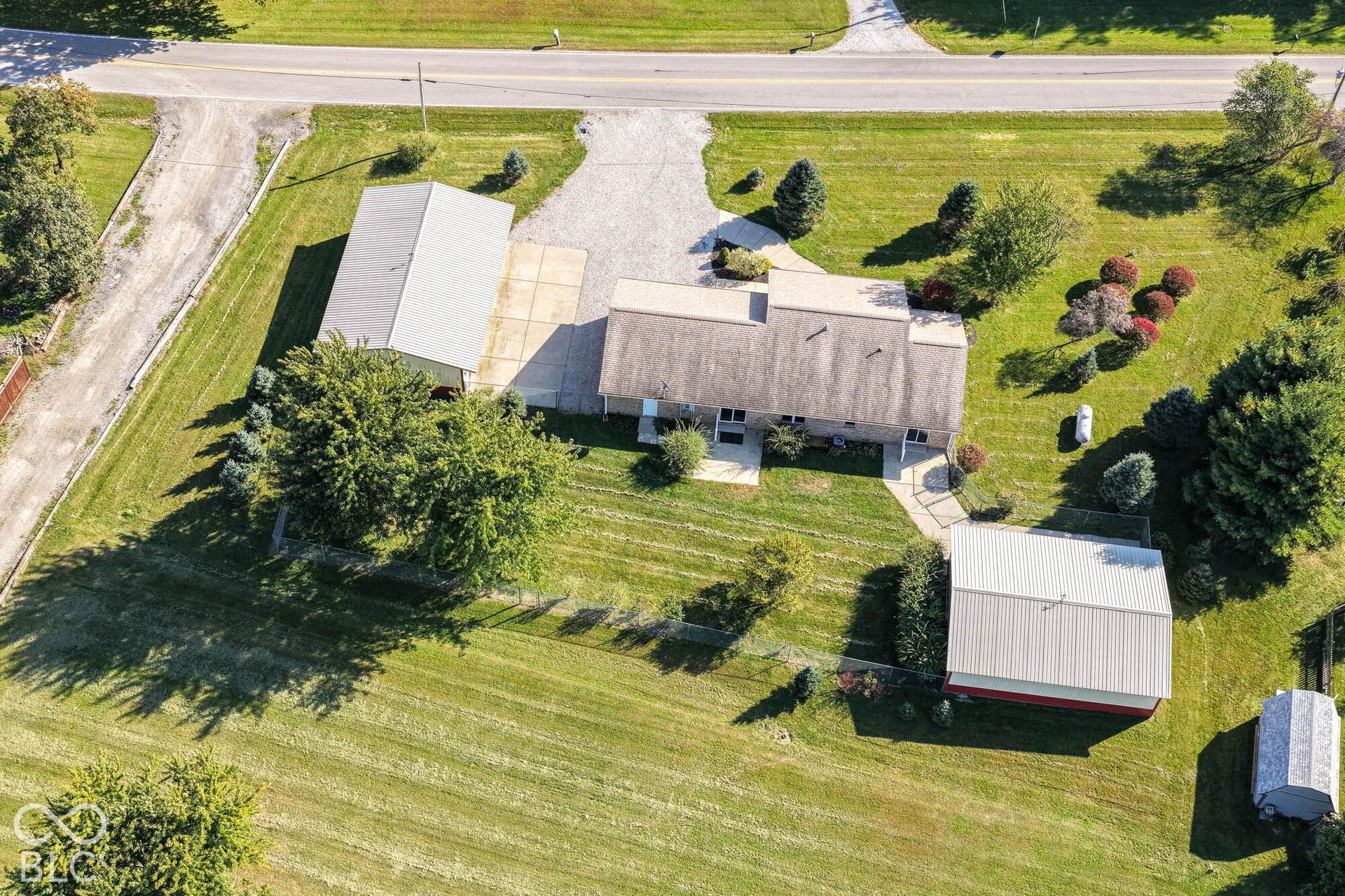Expansive green lawn surrounds the property, featuring a main residence with an asphalt shingle roof