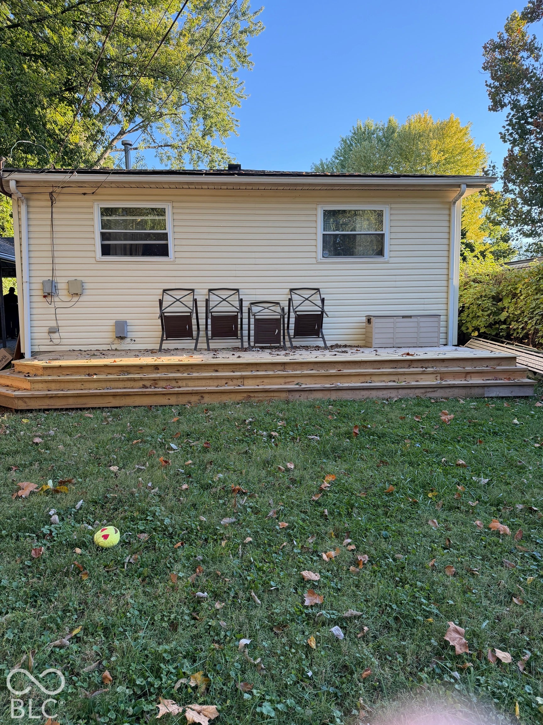 Expansive wooden deck with multiple steps, leading to a large grassy area