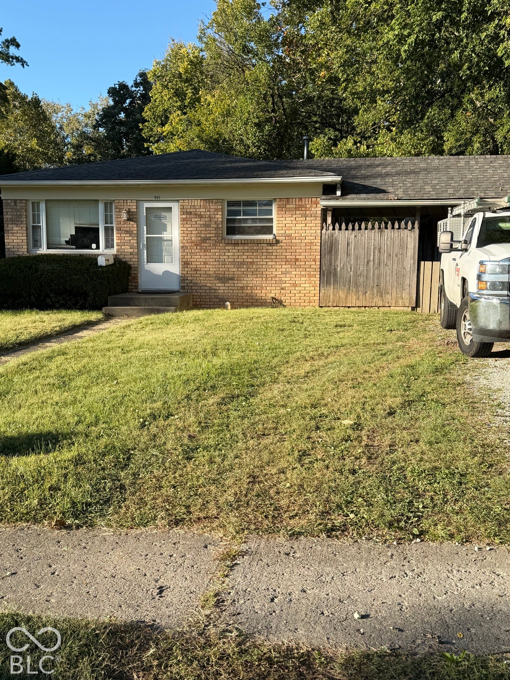 Brick exterior, mature trees, and a wooden privacy fence