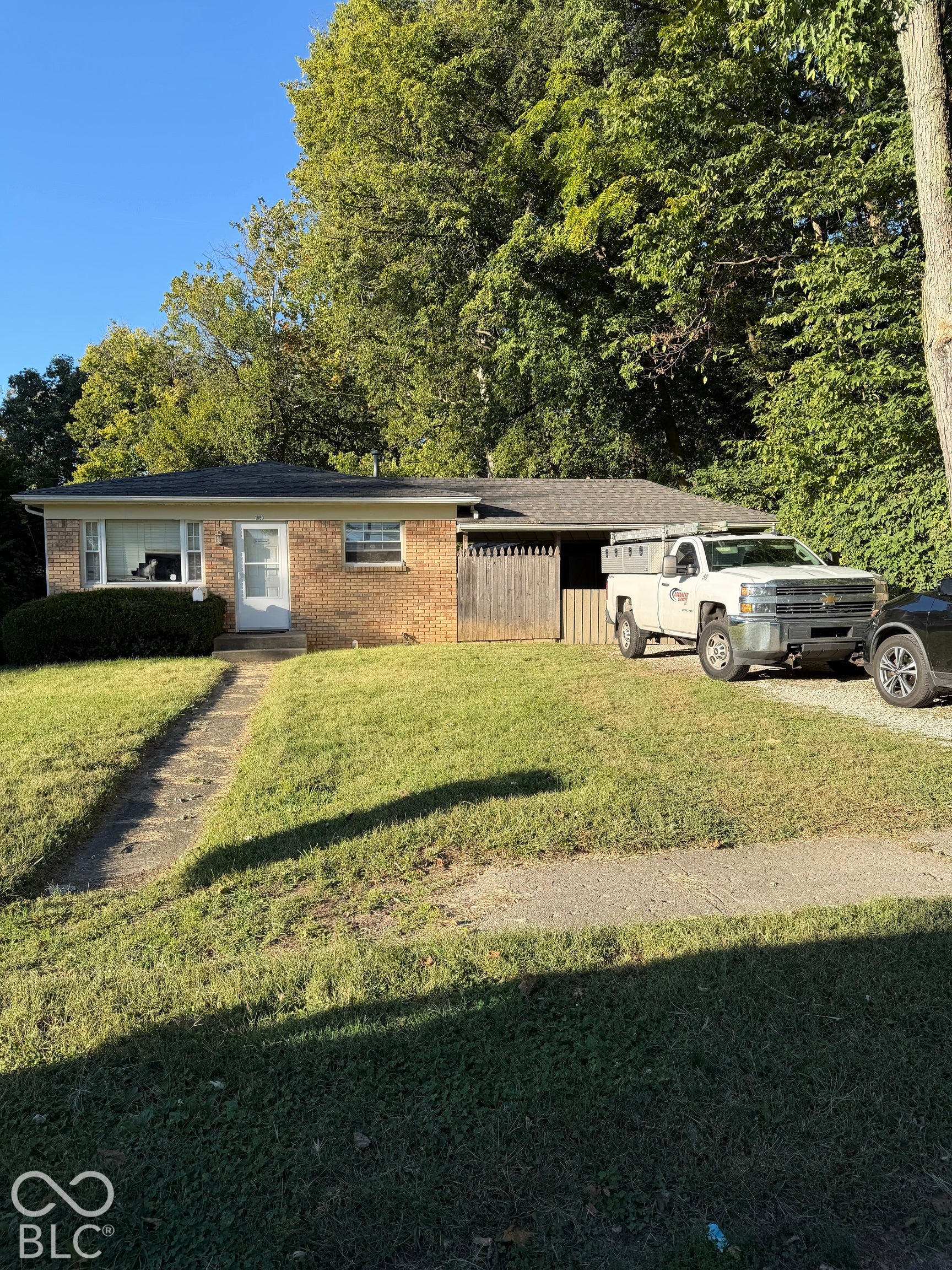 Brick exterior with an attached carport and a shingle roof