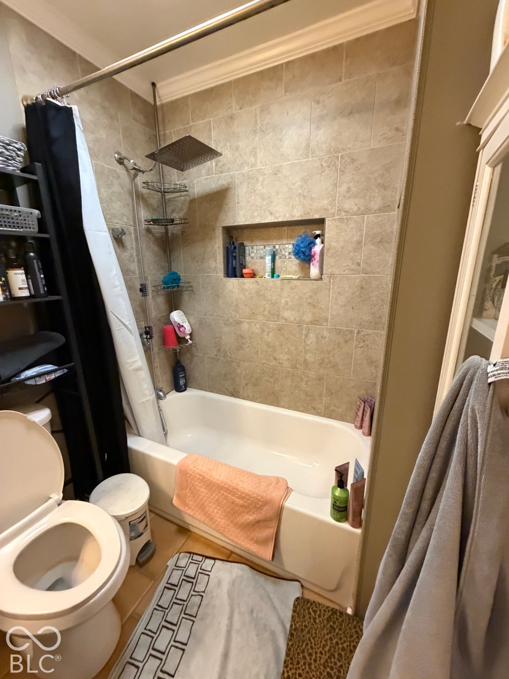 Bathtub and shower combination with a tiled surround, a built-in shower niche, and a rainfall showerhead