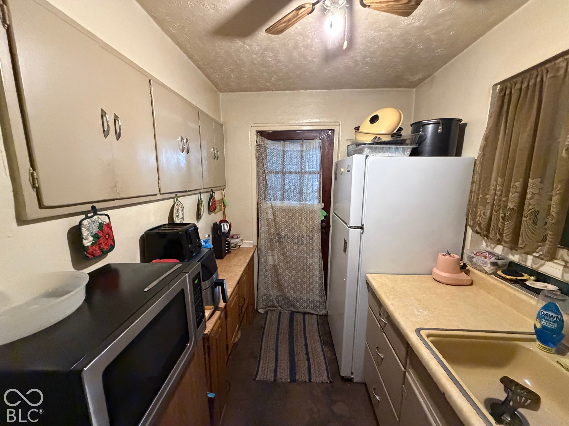 Kitchen featuring upper and lower cabinetry, a double-basin sink, and a ceiling fan