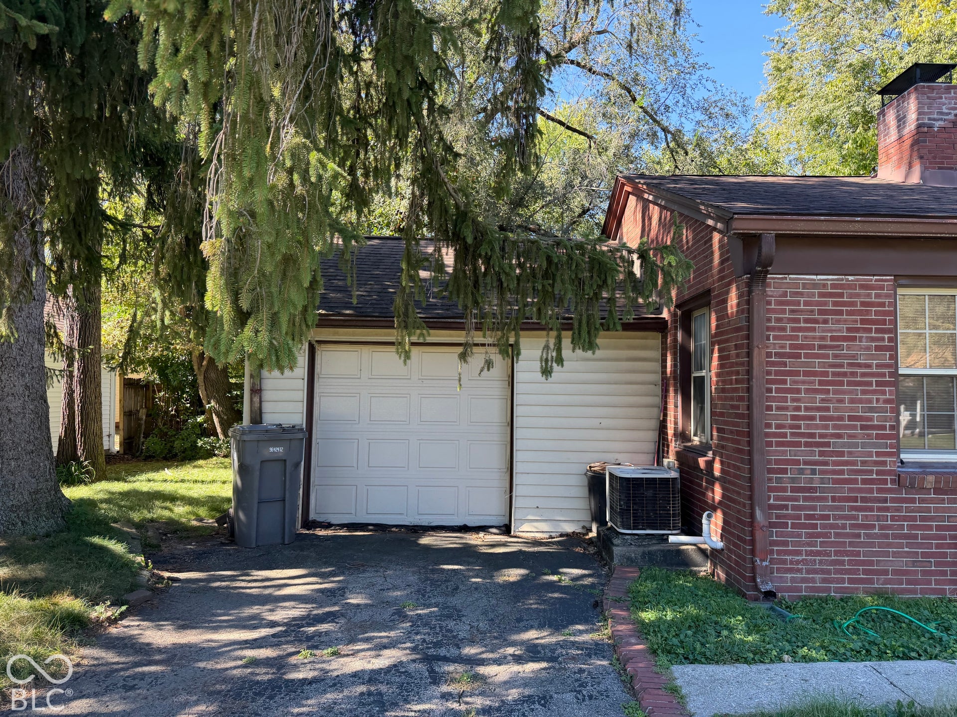 Attached garage with white panel door, brick exterior, and a visible chimney