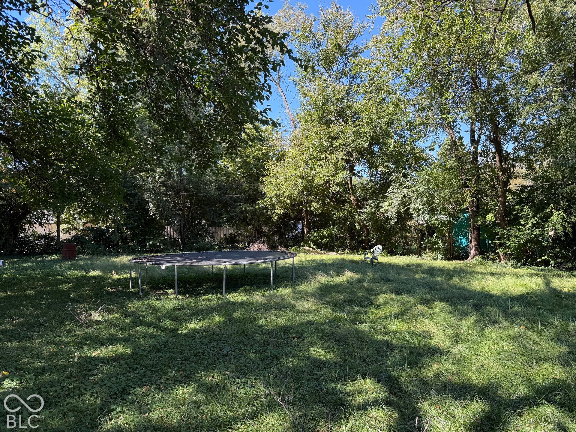 Expansive grassy yard with mature trees providing natural shading
