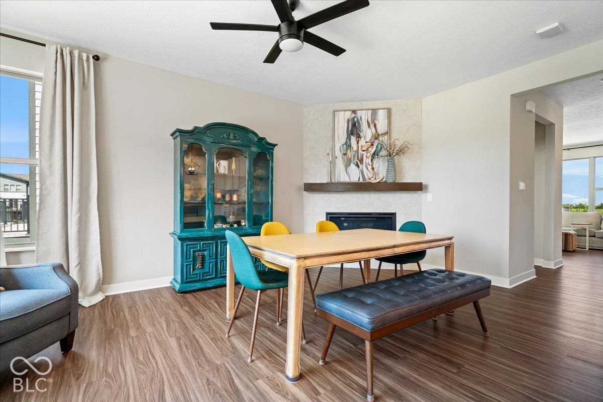 Wood-finish flooring throughout, featuring a corner fireplace with a mantel, and a black ceiling fan