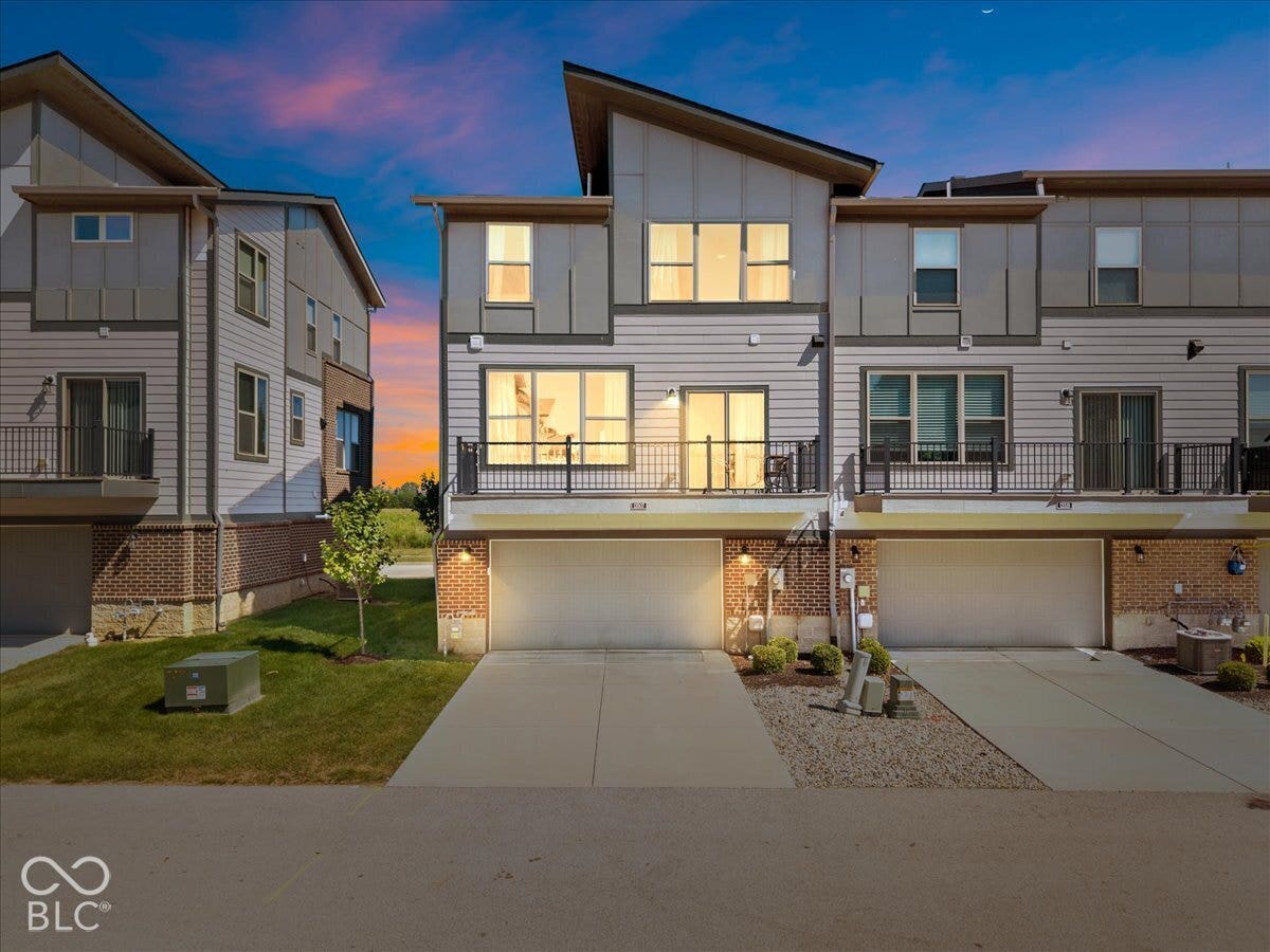 Contemporary multi-level townhome architecture with a sloped roofline, brick and siding exterior, private balconies with metal railings, and integrated garage spaces