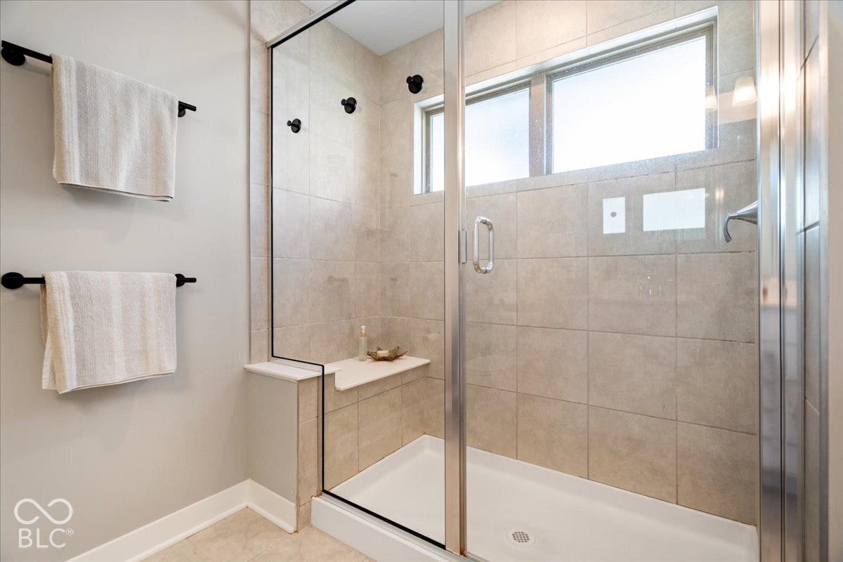 Glass-enclosed shower with tile surround, built-in bench, and multiple shower heads