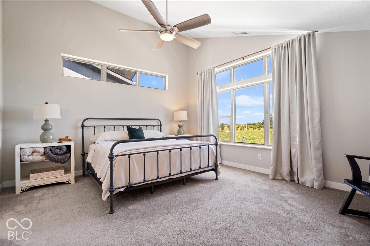 Vaulted ceiling with an attached ceiling fan, large picture windows, clerestory windows, and light gray wall finishes