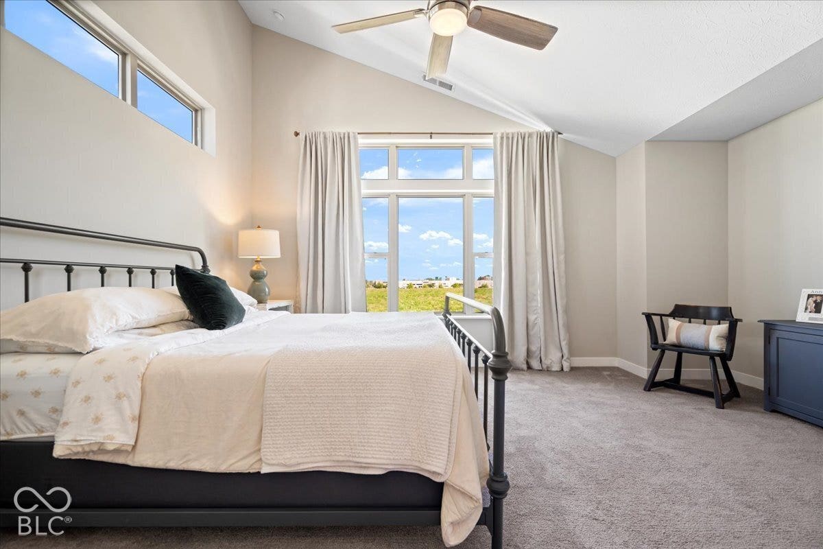 Vaulted ceiling with a ceiling fan, transom windows, and a large picture window with curtains