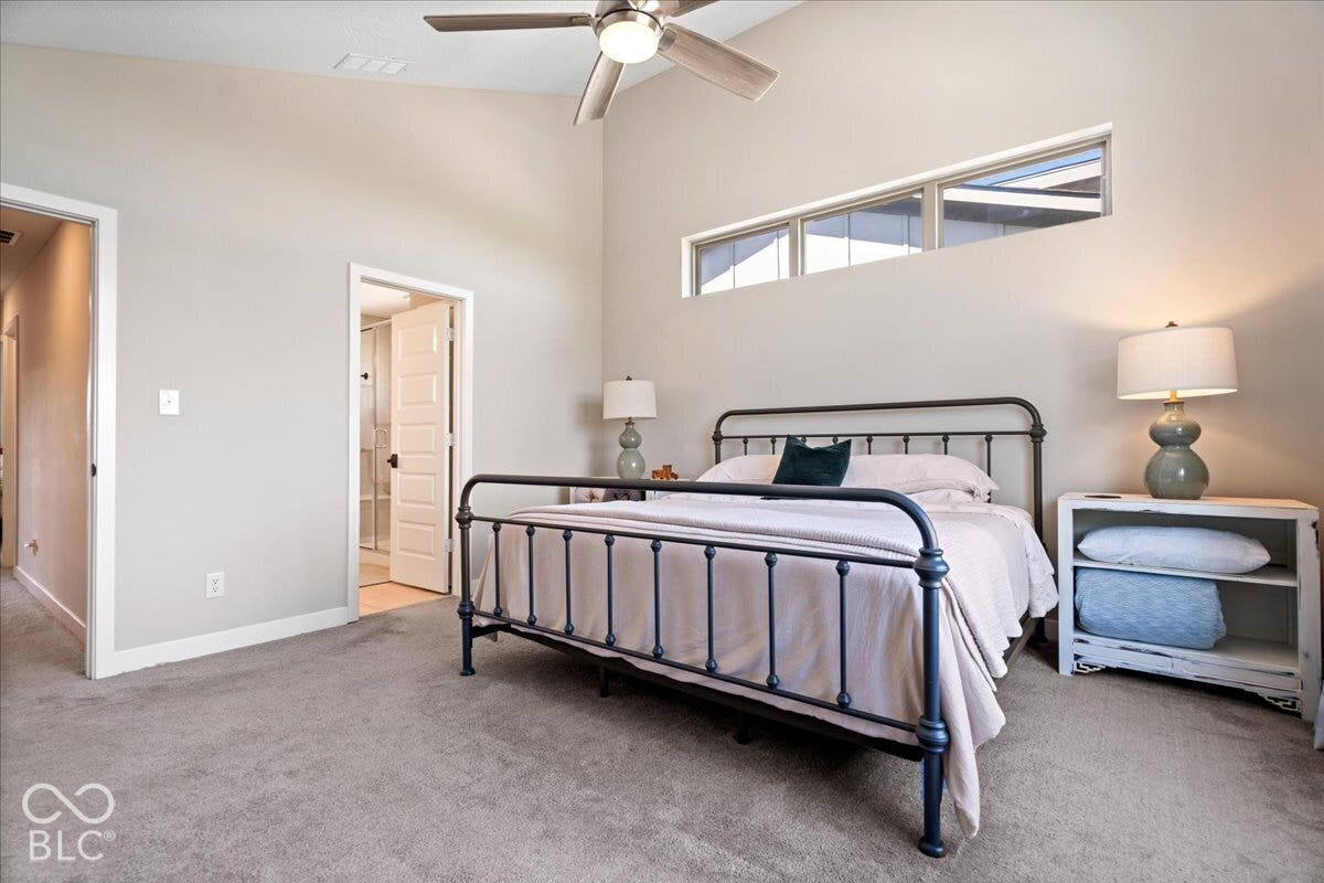 Vaulted ceiling with a ceiling fan, high-set windows, gray carpet, and an en-suite bathroom with a glass-enclosed shower