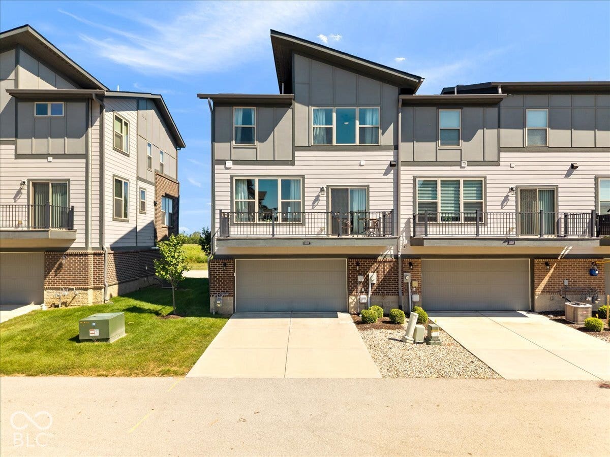 Modern townhome exterior featuring multi-level architecture, a combination of horizontal siding and paneling, and an integrated two-car garage