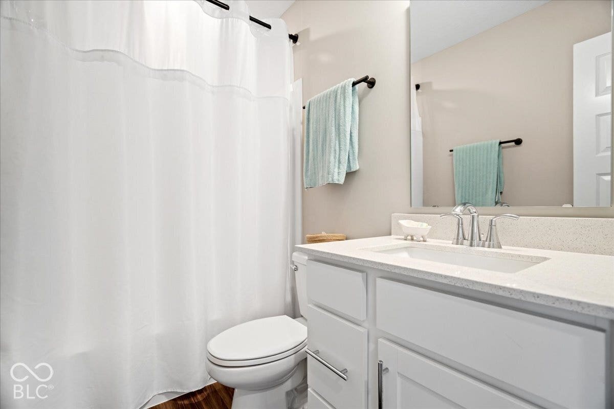 Bathroom featuring a single vanity with white cabinetry, a light-colored countertop, and a chrome faucet