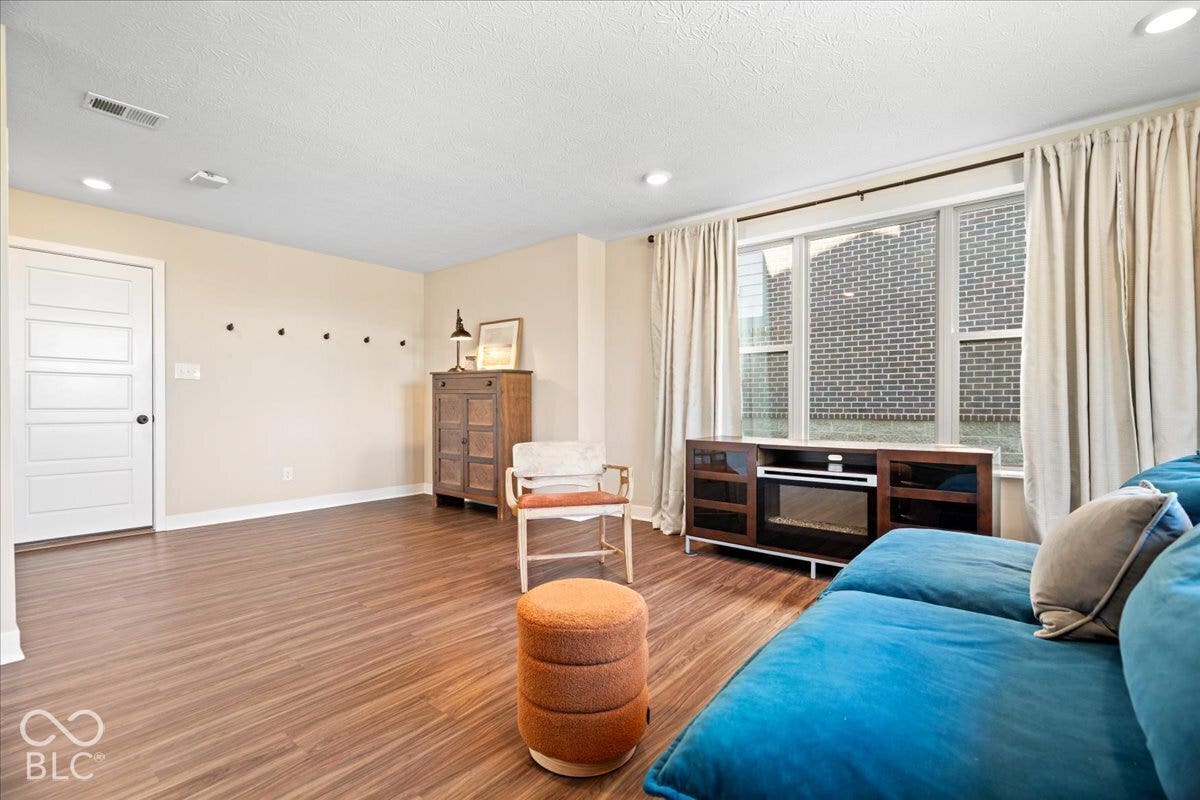 Wood-finish flooring, recessed lighting, white trim, and a built-in media console with an electric fireplace