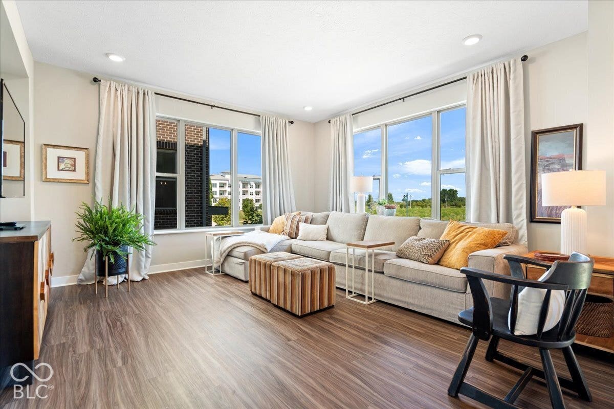 Spacious living area featuring wood-finish flooring, recessed lighting, and large windows with extensive natural light