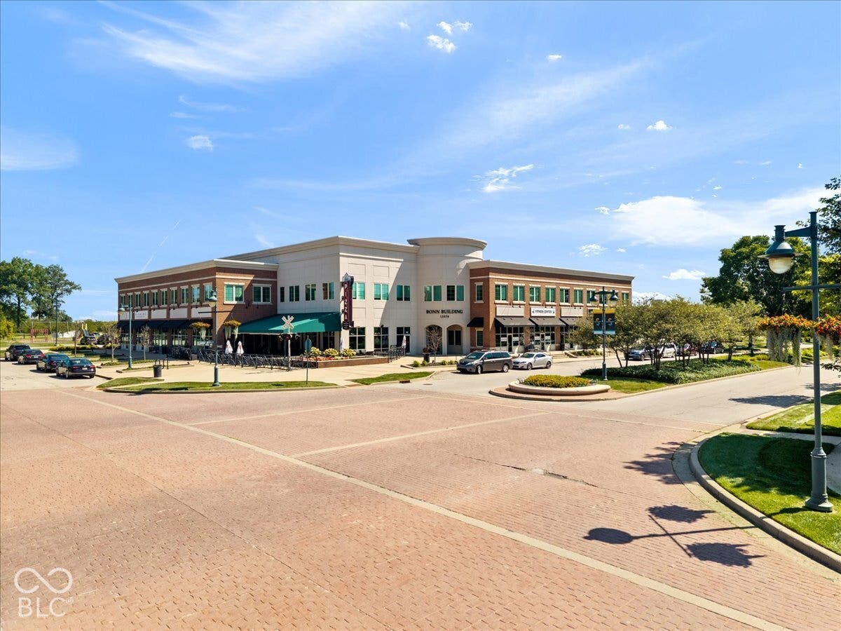 Commercial building with brick and stucco facade, ground-level retail storefronts, second-story windows, and an outdoor seating area