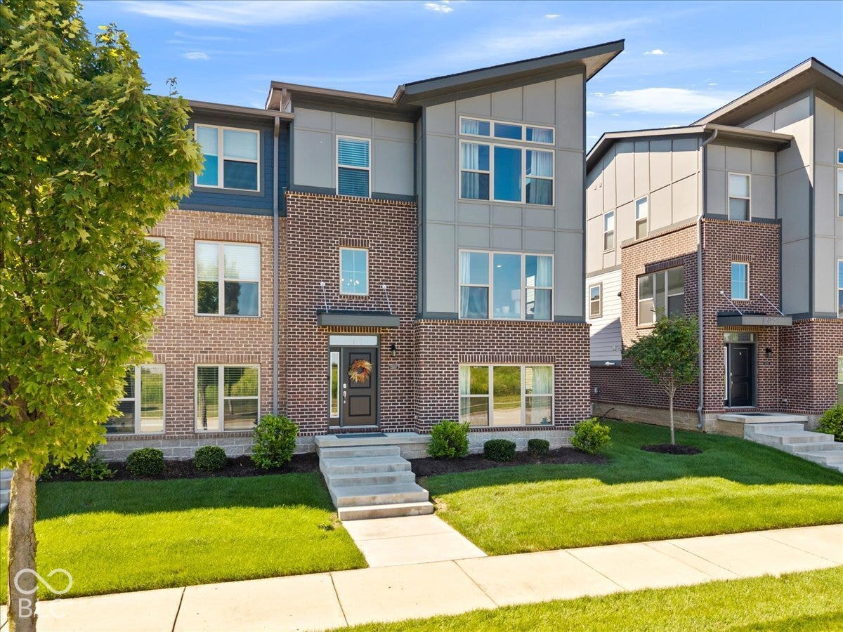 Contemporary exterior featuring brick and siding, large windows, an integrated awning, and a concrete walkway