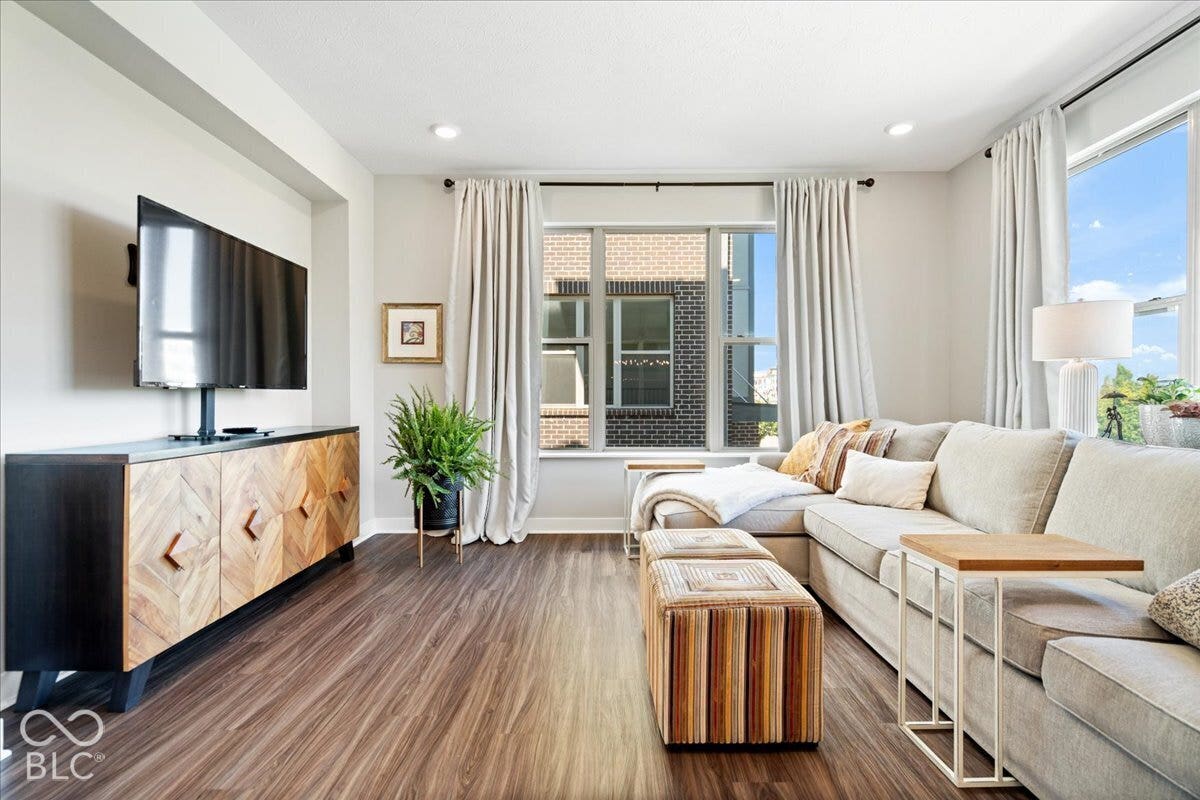 Wood-finish flooring throughout, recessed lighting, and large windows with permanent curtain rods