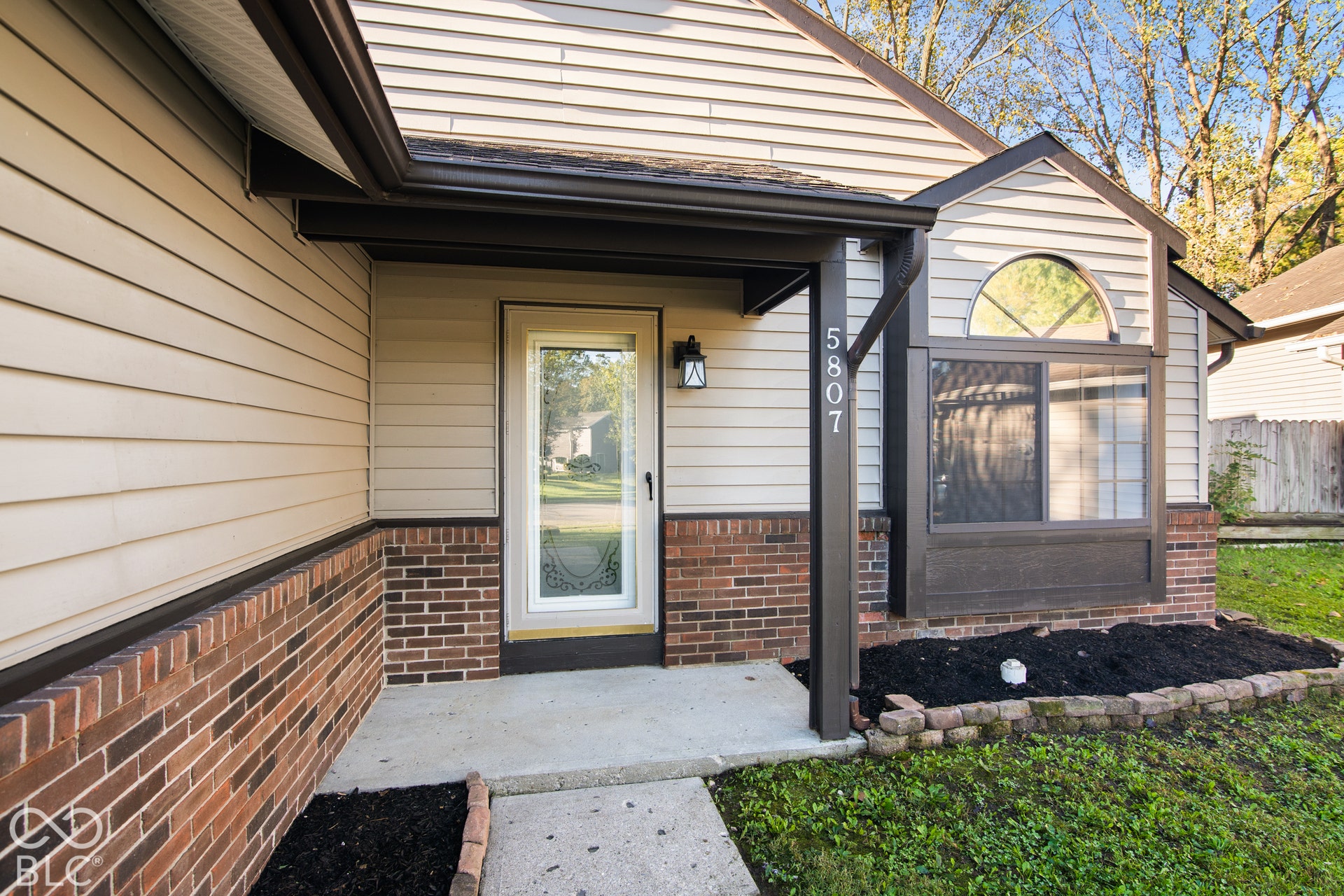 Exterior with brick detailing, horizontal siding, an arched window, a full-light entry door, and a covered entryway