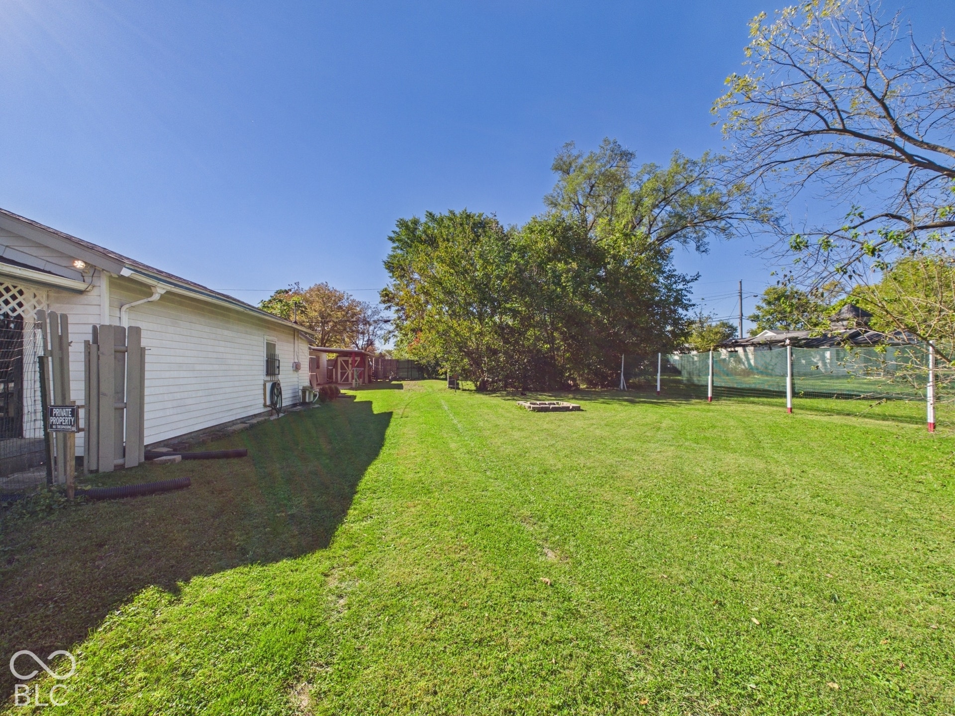 Expansive lawn area with a white siding exterior and mature trees