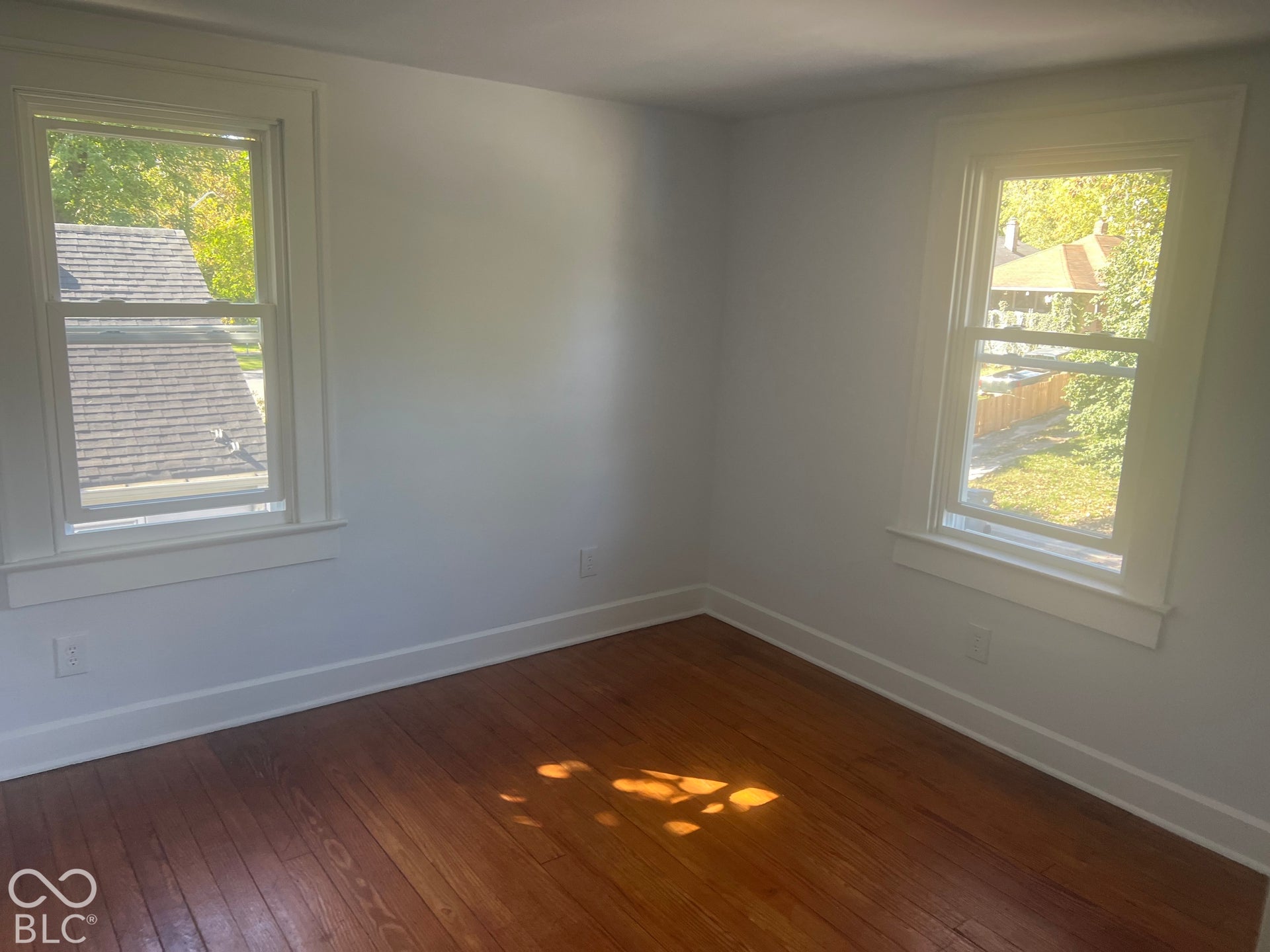 Hardwood flooring, multiple windows, window trim, white wall finishes