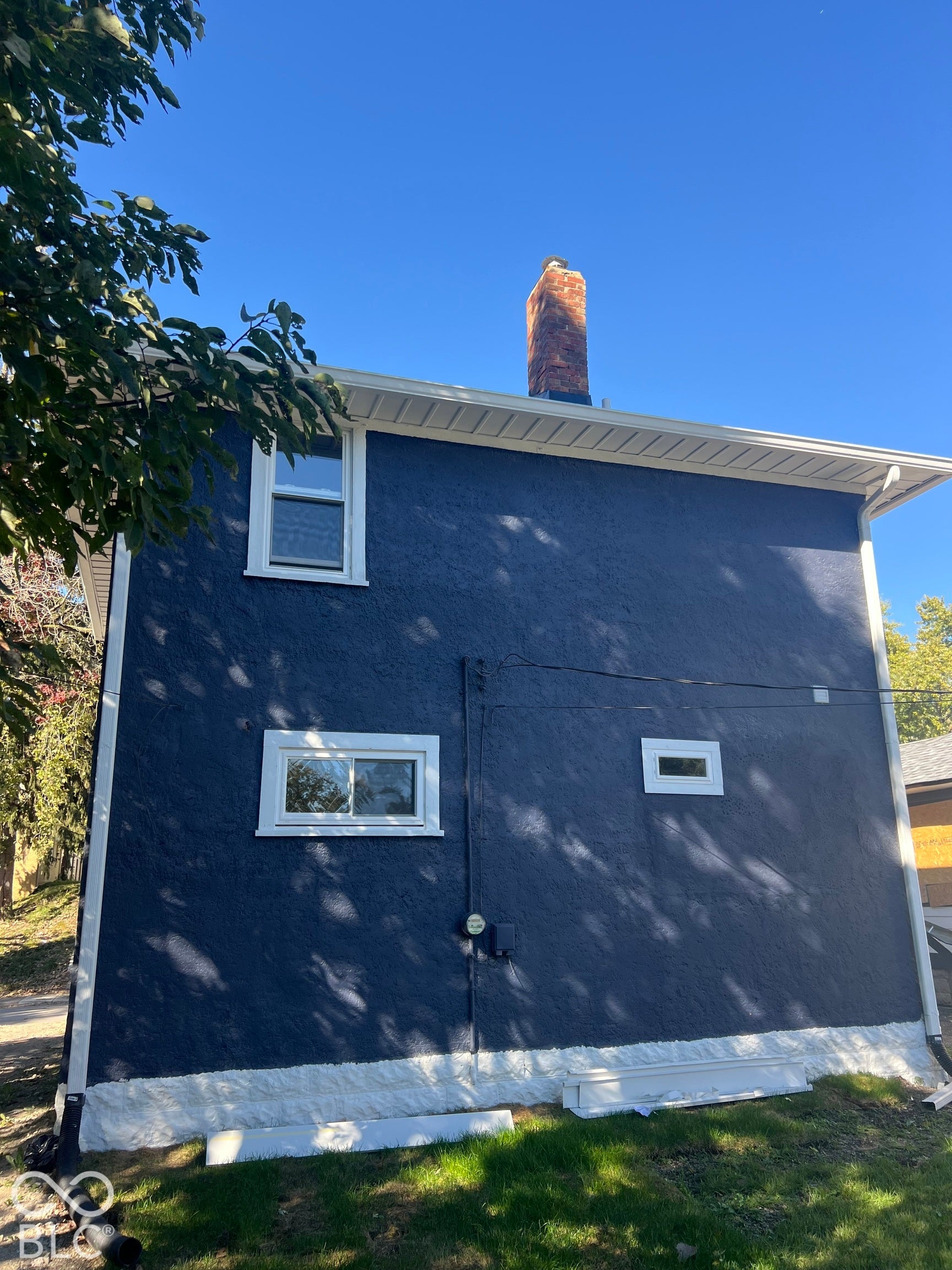 Stucco exterior with a brick chimney and white trim