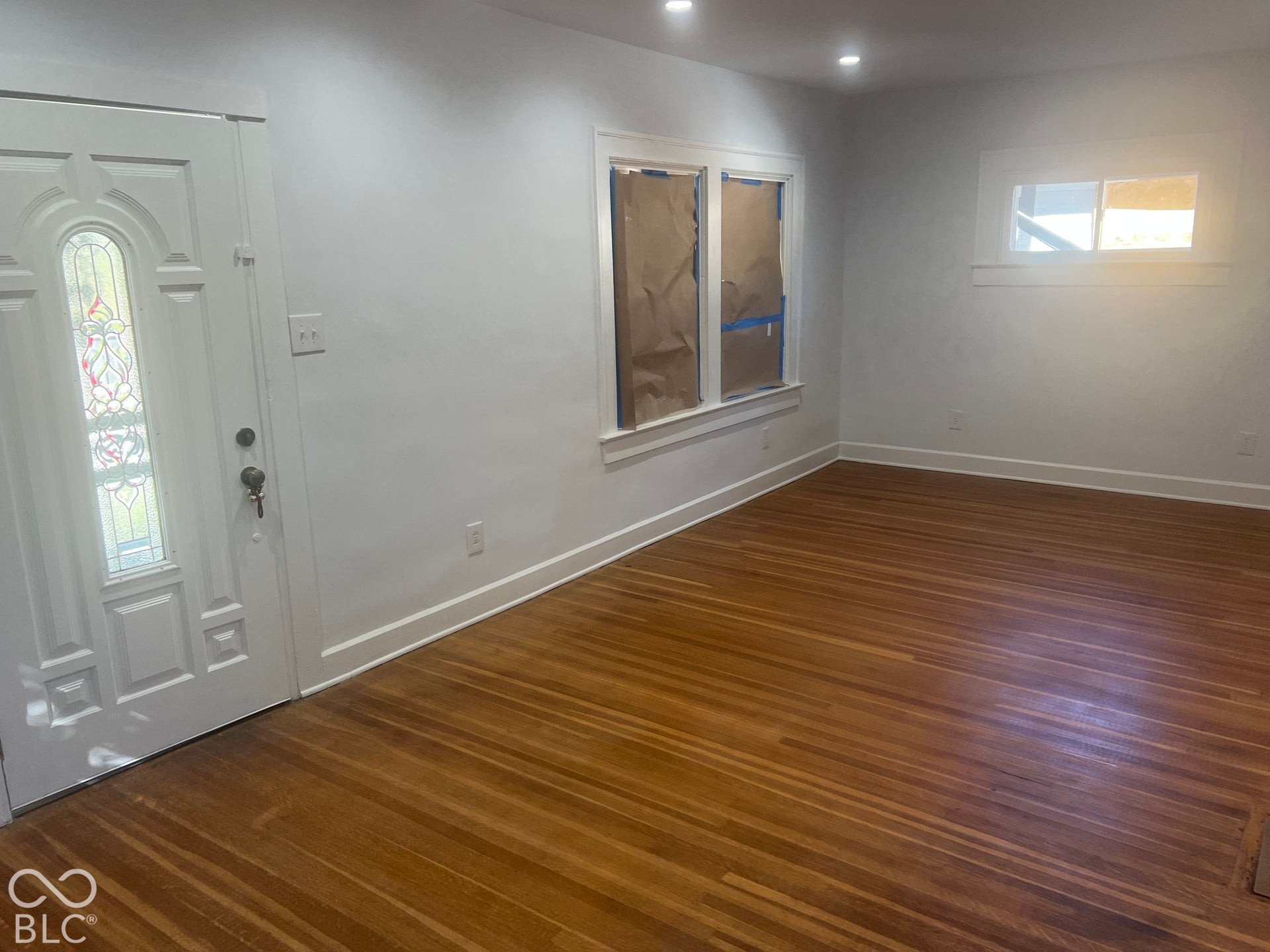 Hardwood flooring, recessed lighting, white trim, and a decorative glass entry door