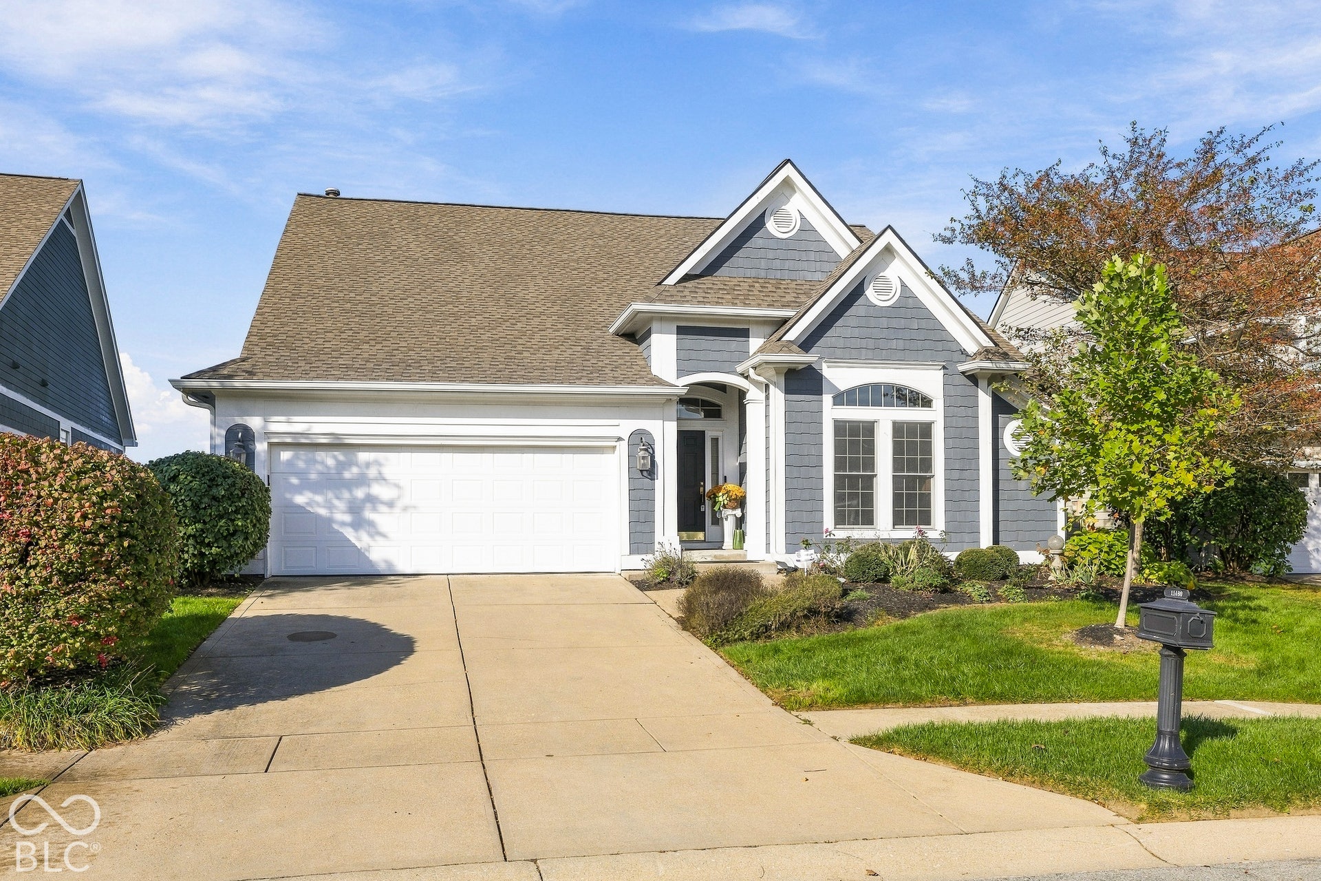 Exterior facade featuring grey shake and horizontal siding, a gabled roofline, arched window detailing, and a multi-car garage with a concrete driveway