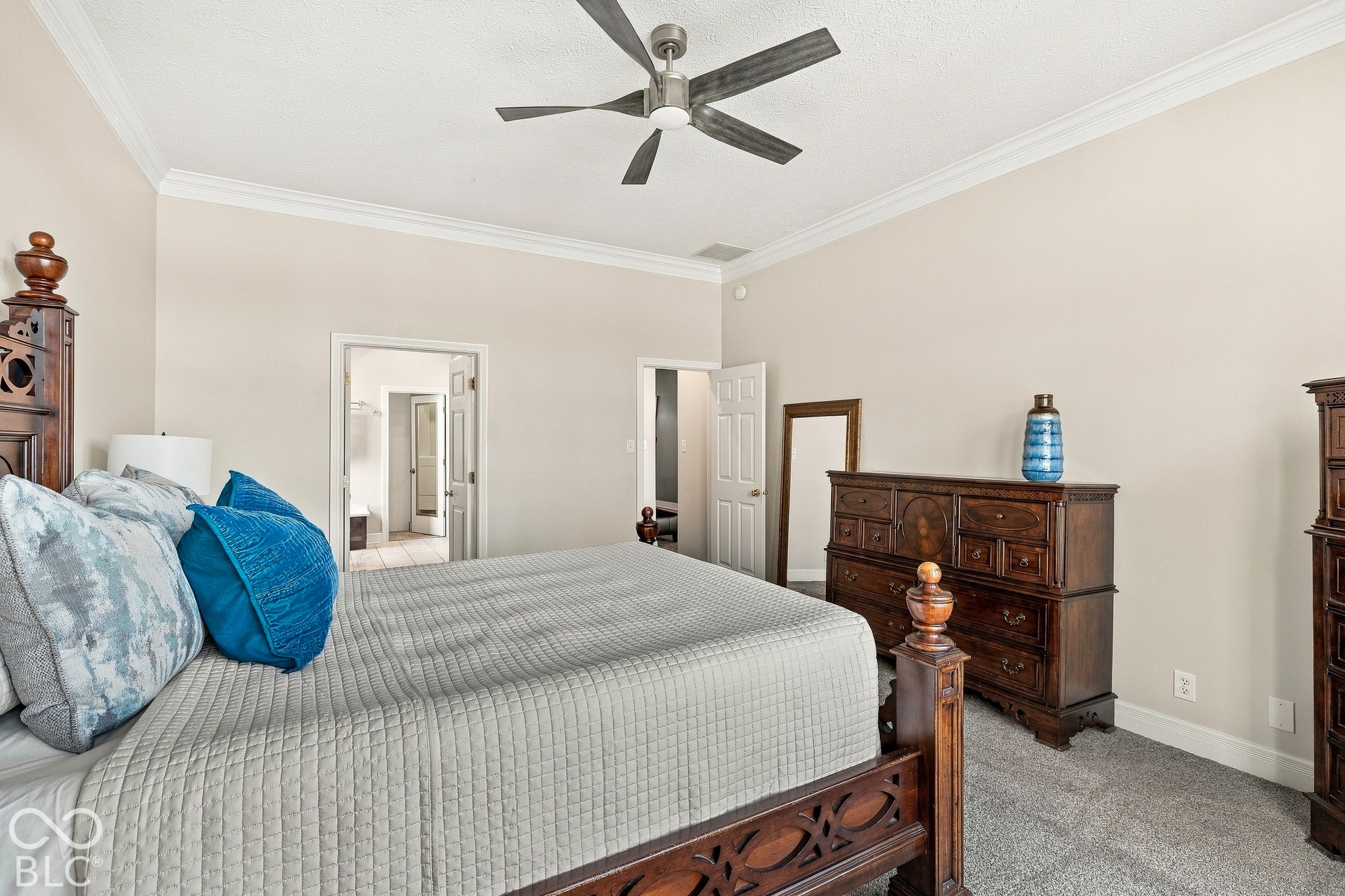 Neutral-toned room featuring crown molding, carpeting, and a central ceiling fan