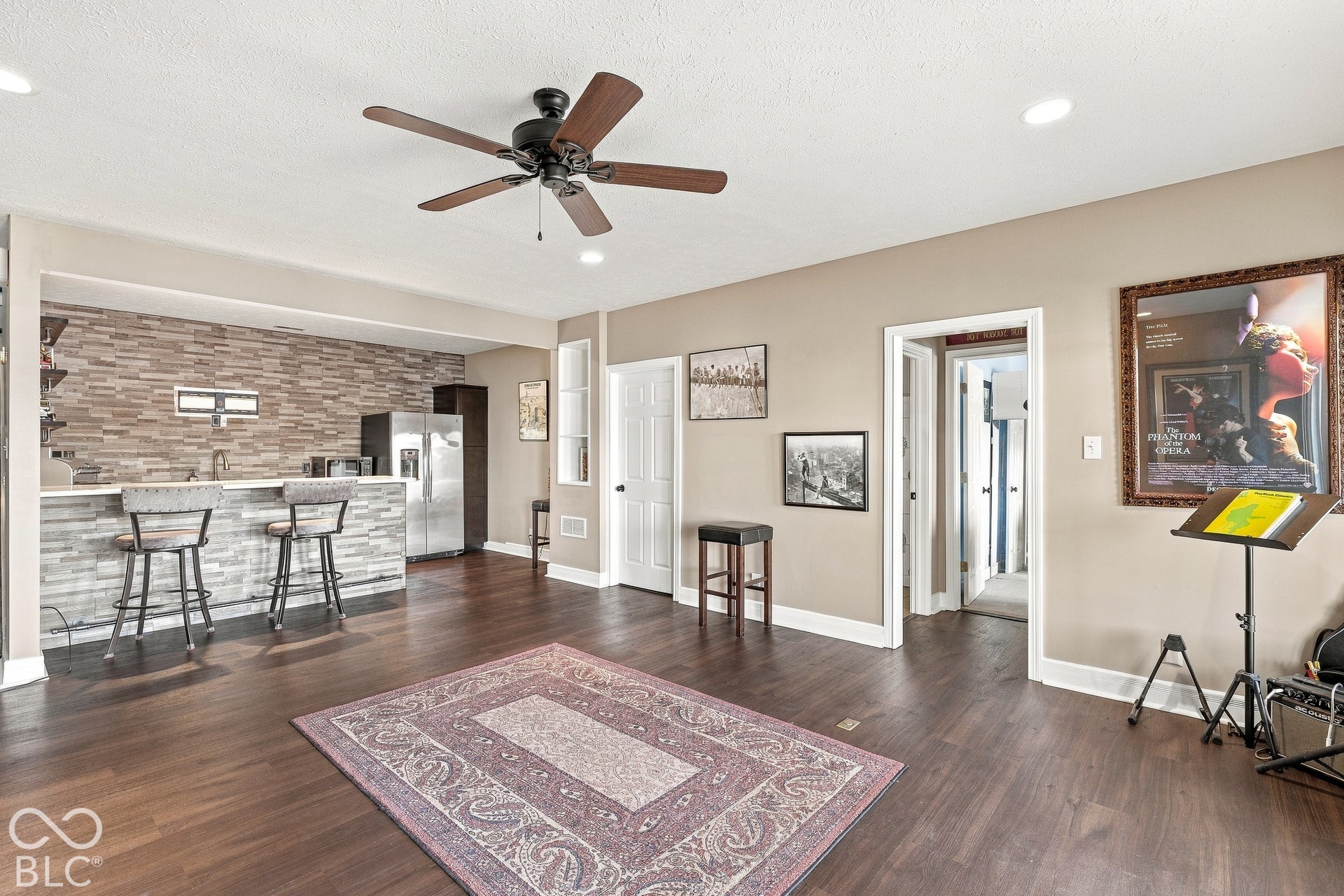 Wood-finish flooring, wet bar with a stacked stone backsplash, and recessed ceiling lighting