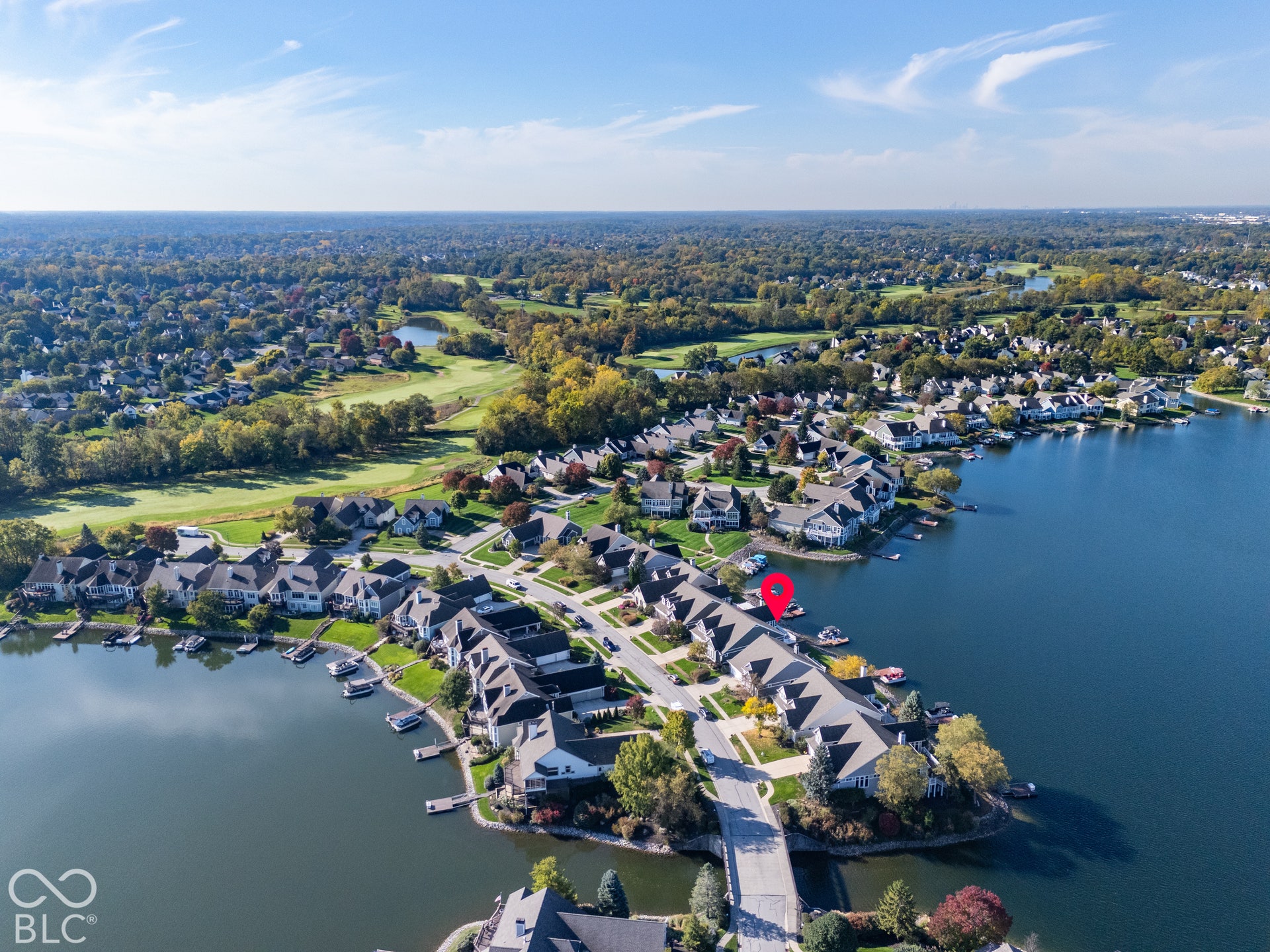 Aerial perspective of a waterfront residential property featuring direct water access, private boat docks, and proximity to expansive green space